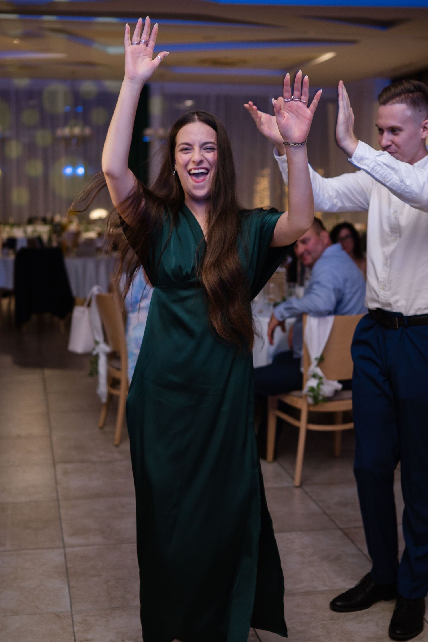 Wedding guests dancing and celebrating with raised hands on dance floor.
