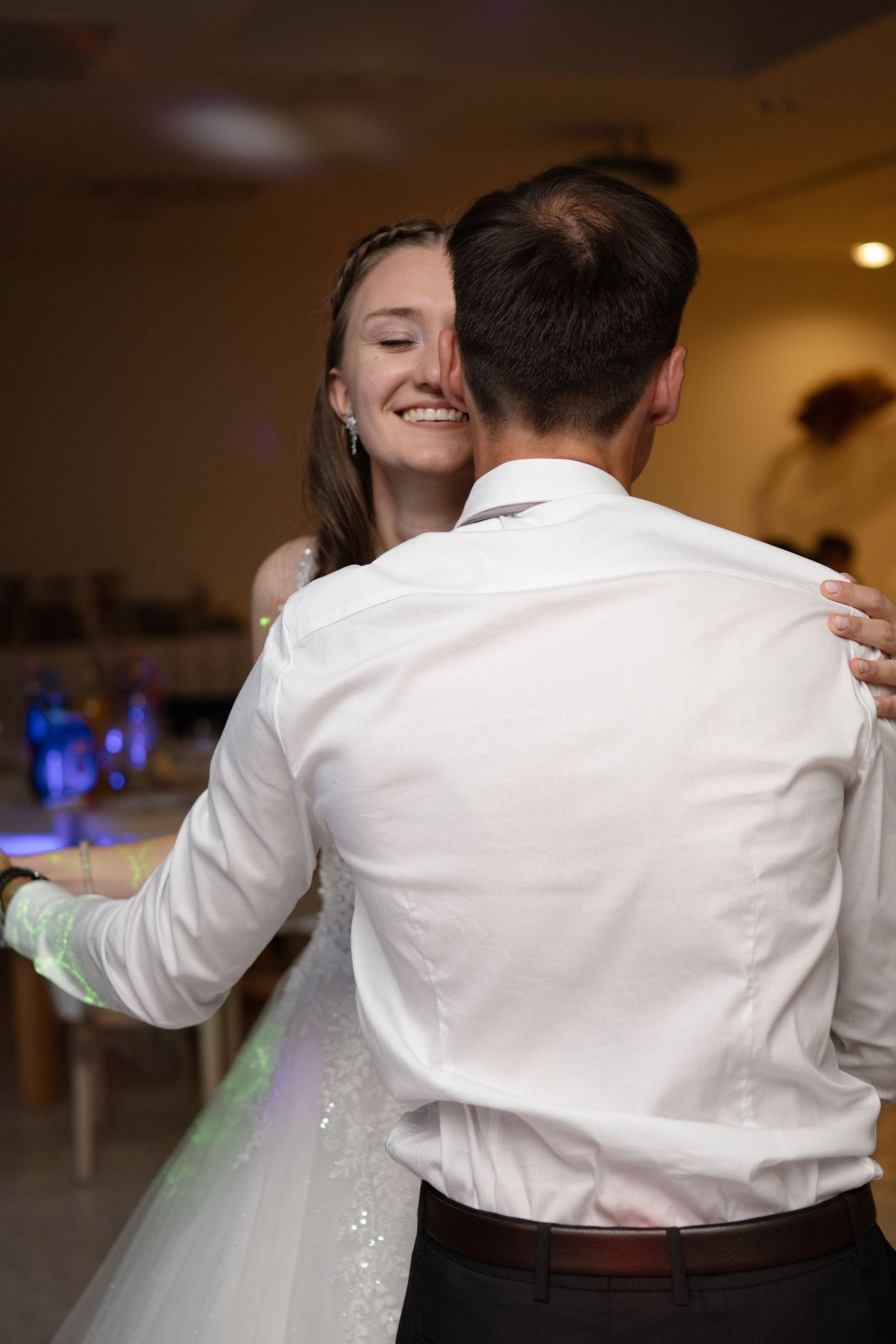 A couple shares their first dance at a wedding reception with joyful expressions.