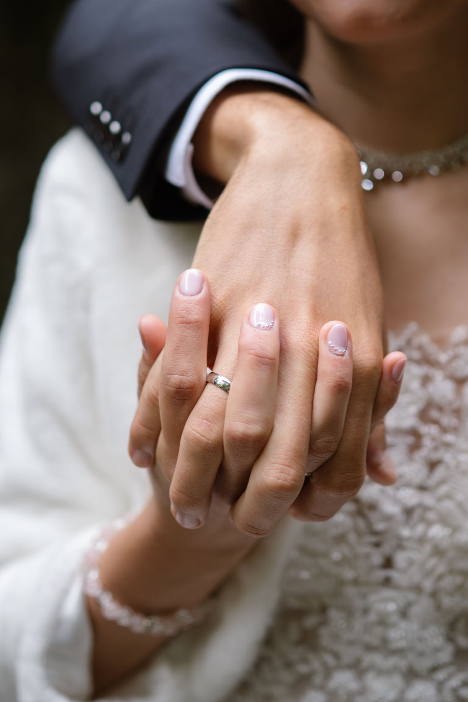 Close-up of an engagement ring on a bride's hand with delicate lace details.