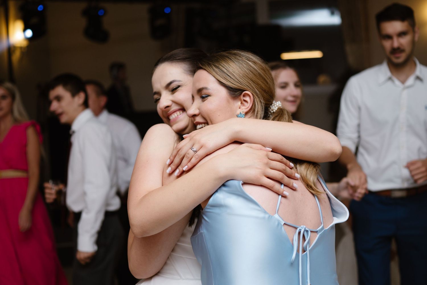 Two wedding guests share an emotional embrace on the dance floor during the reception.