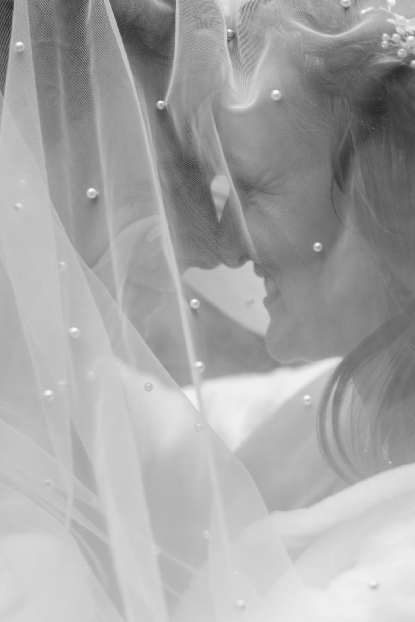 An intimate moment captured through a delicate white wedding veil.