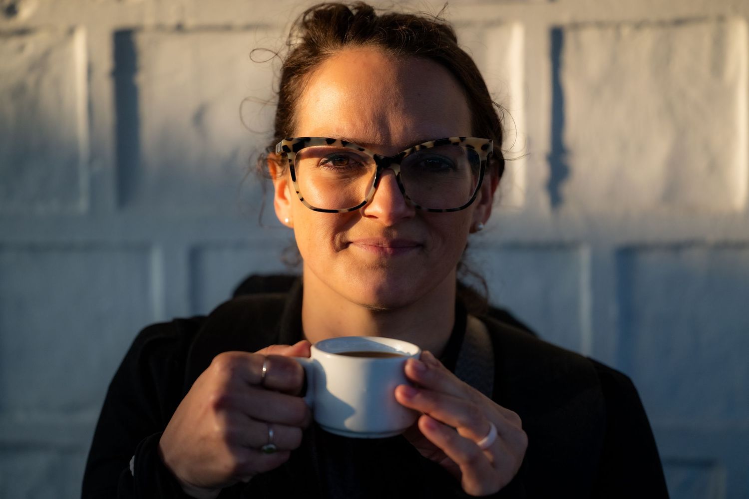 Portrait of a woman drinking coffee in natural light.
