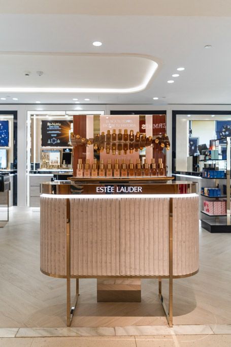 expositor de cosmética Estee Lauder en centro comercial con diseño elegante e iluminación moderna