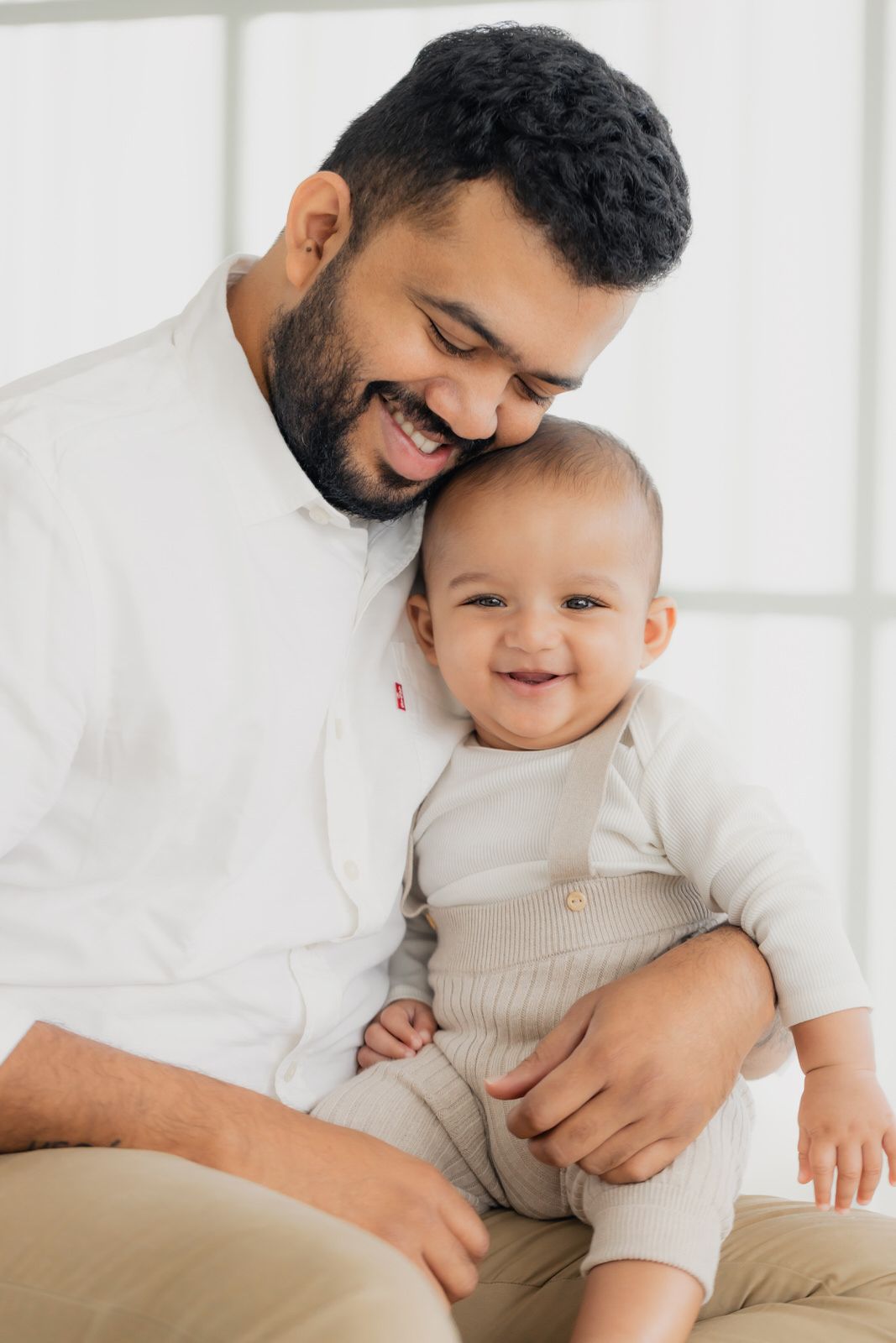 A tender moment between parent and baby captured against a bright white background.