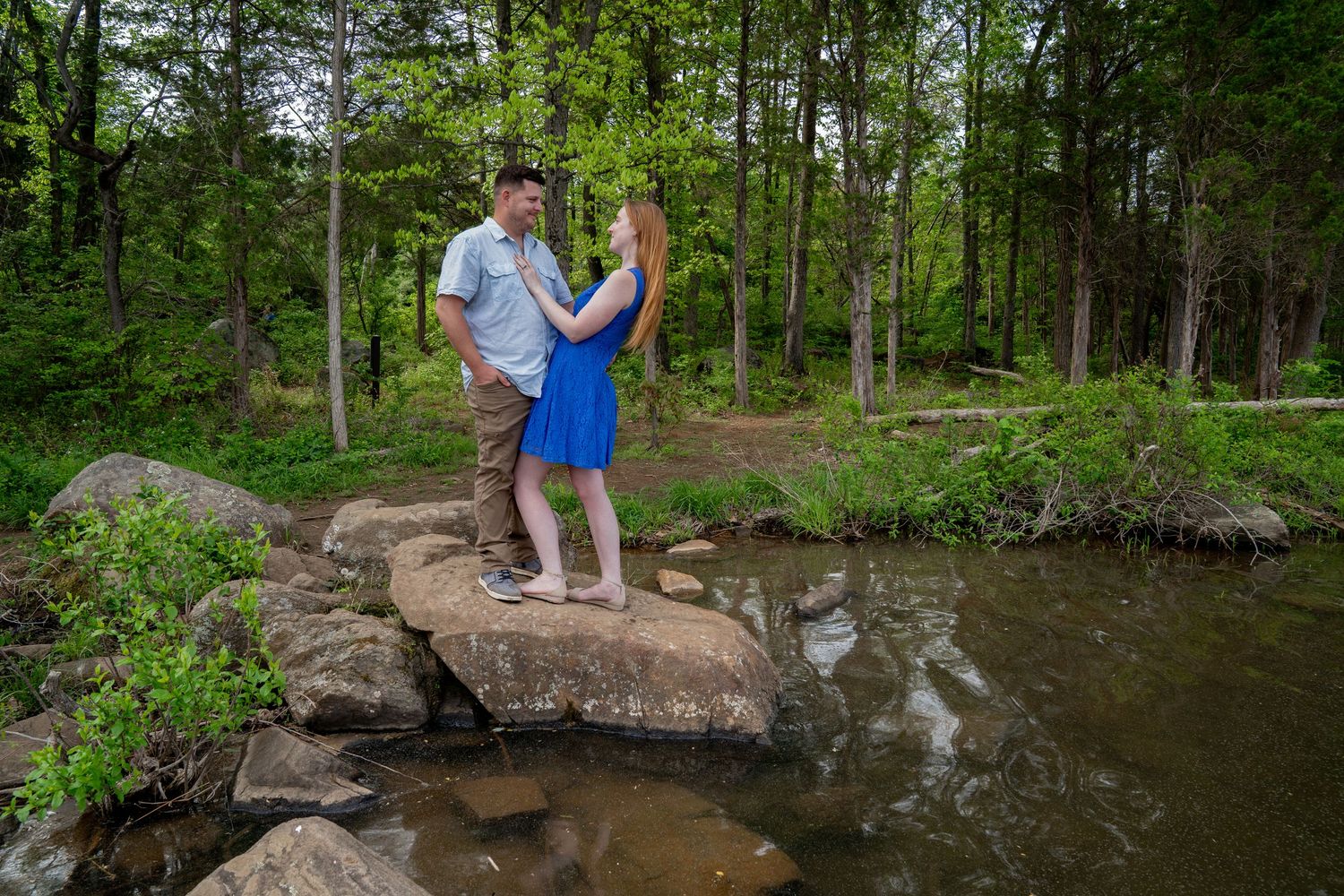 Couple enjoying a scenic moment together on rocks by a forest stream.