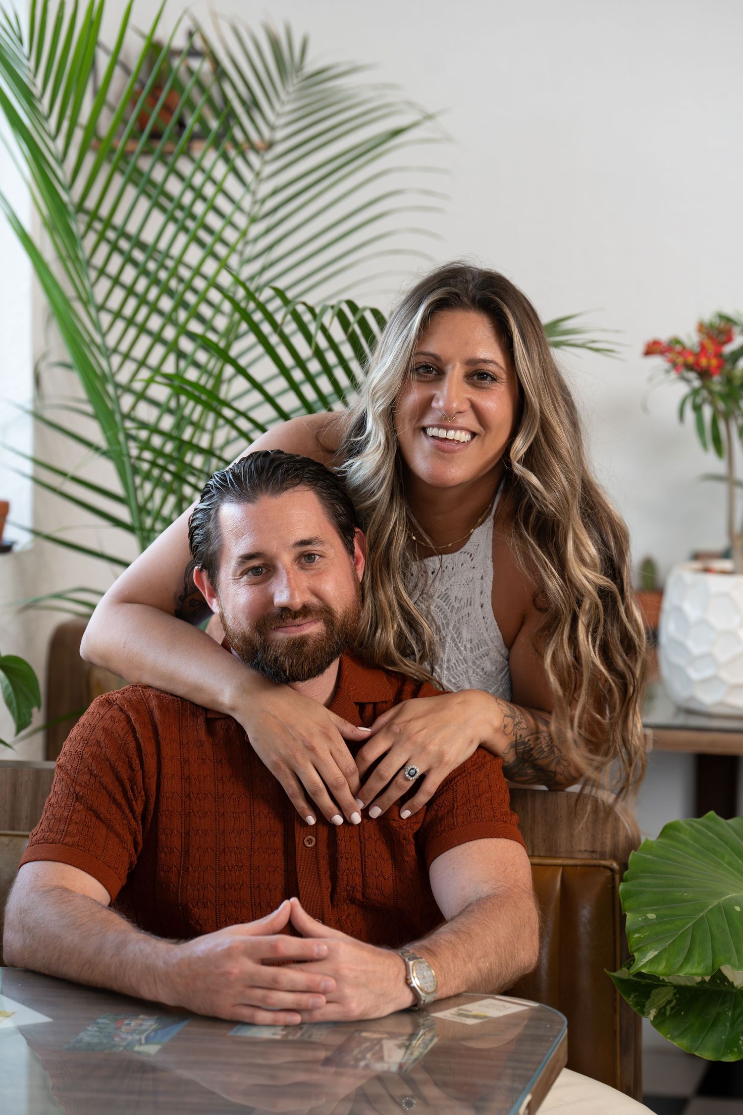 Intimate portrait with tropical plants and warm lighting in modern home interior.