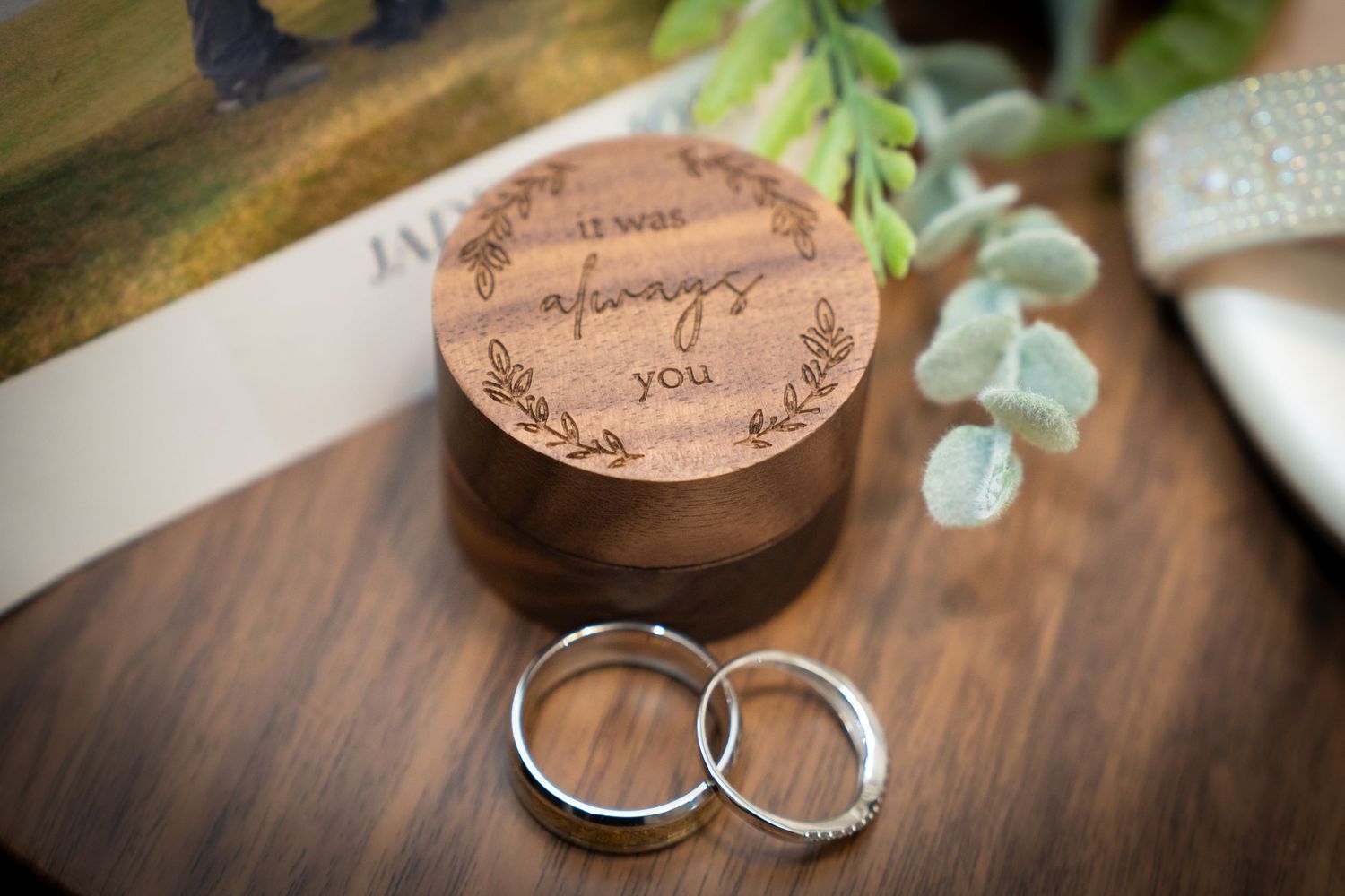 Wooden coasters, tea lights, and decorative objects arranged with eucalyptus leaves on dark table surfaces.