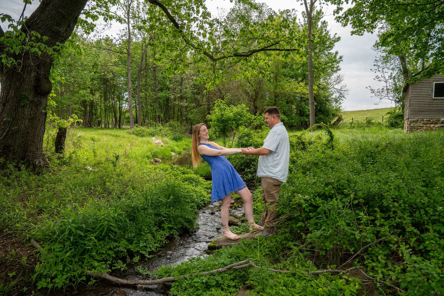 Wide landscape view of a couple's engagement session in a scenic park setting.