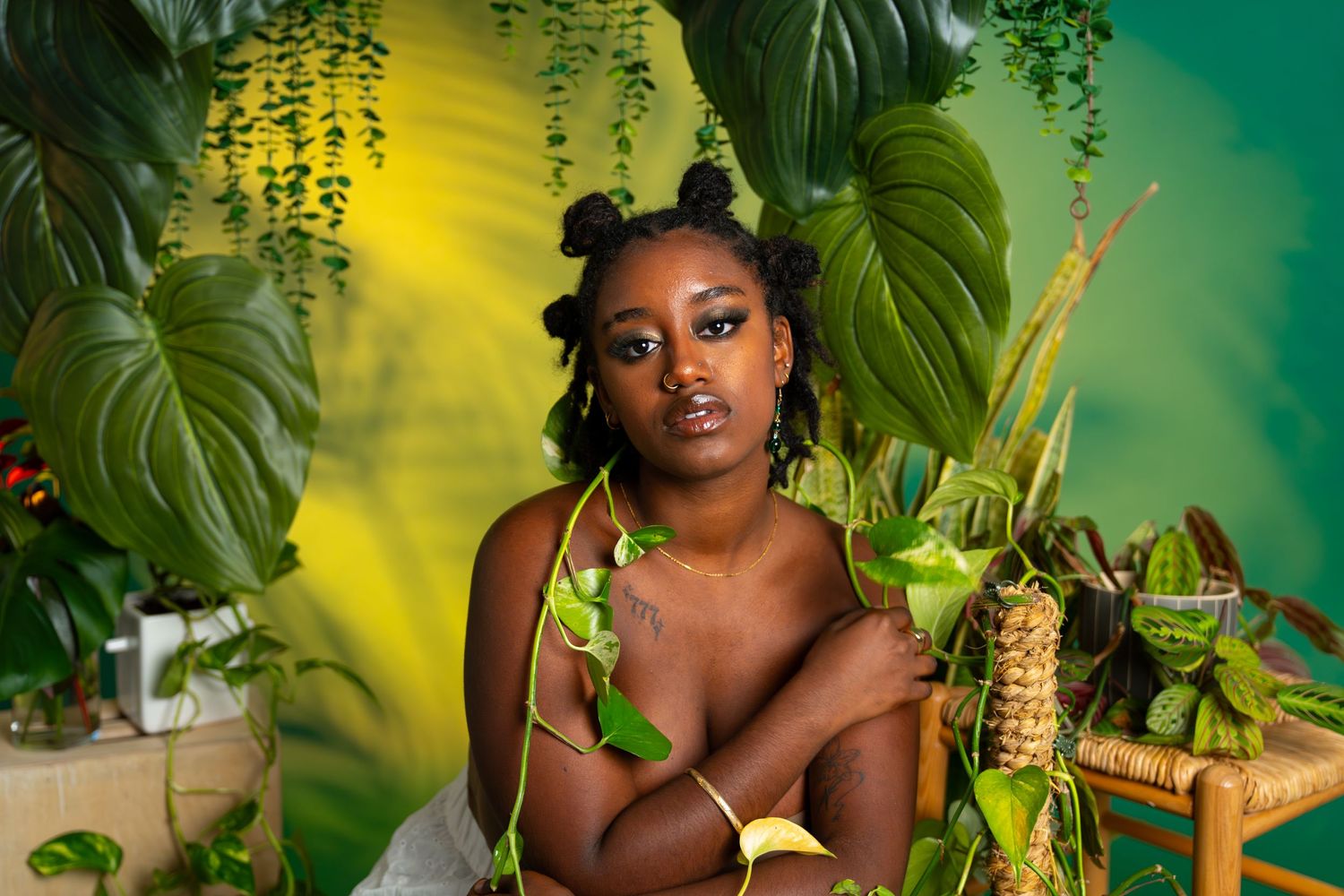 Artistic portrait session in a tropical setting with hanging plants and vibrant green-yellow lighting.