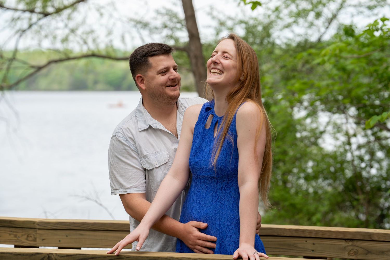 Happy couple sharing a joyful moment by a lake surrounded by spring greenery.
