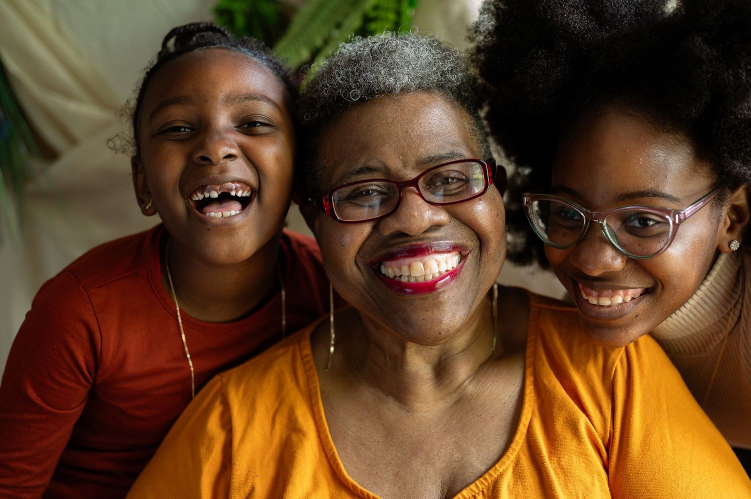 Three generations share joyful laughter while wearing glasses in a warm family portrait.