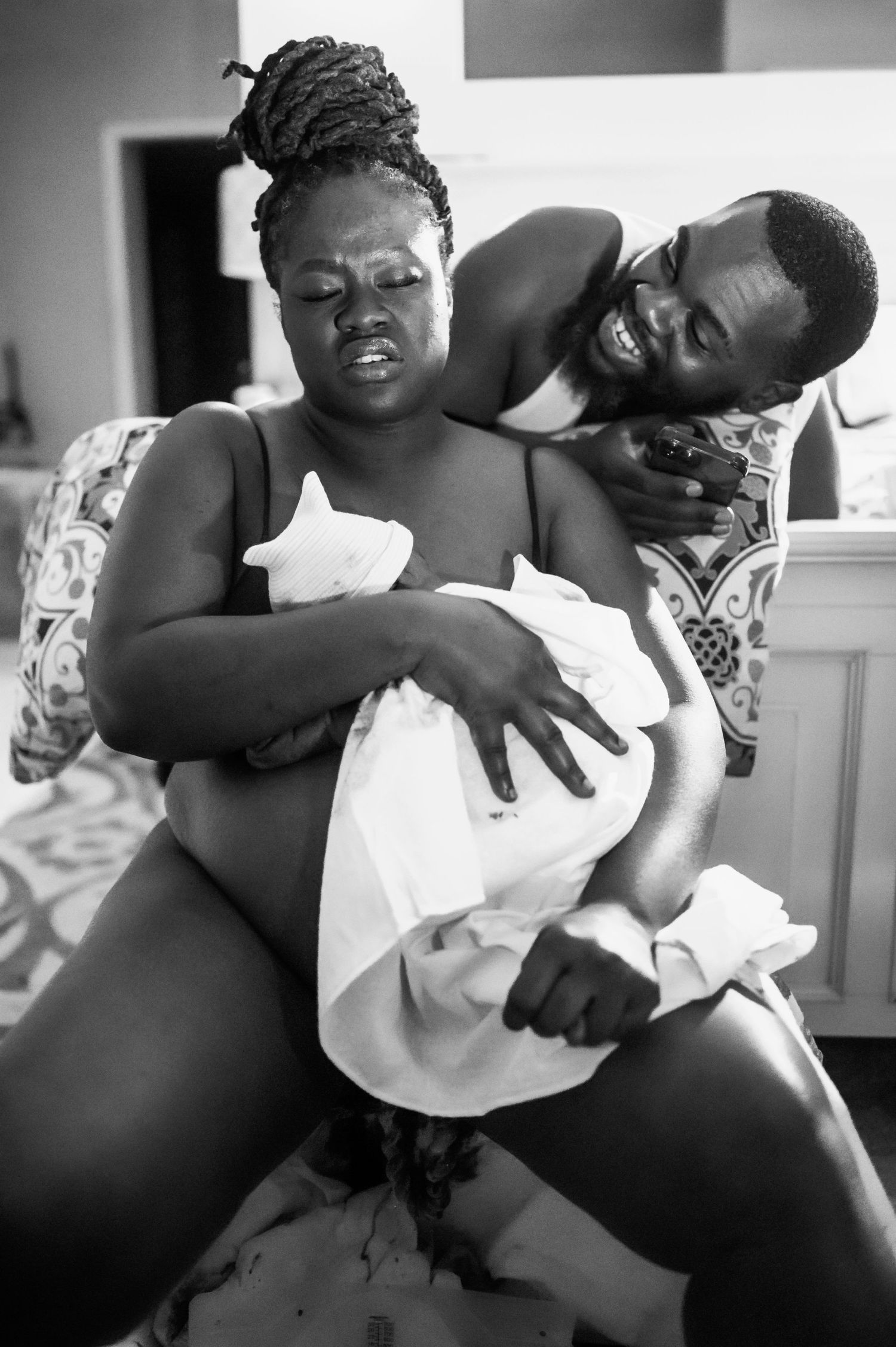 Intimate black and white photograph capturing a tender moment during childbirth.