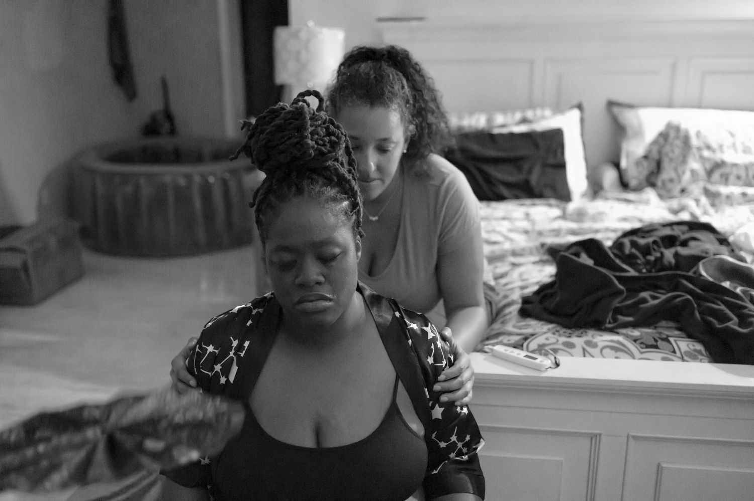 Intimate black and white photograph of a doula providing comfort during labor.