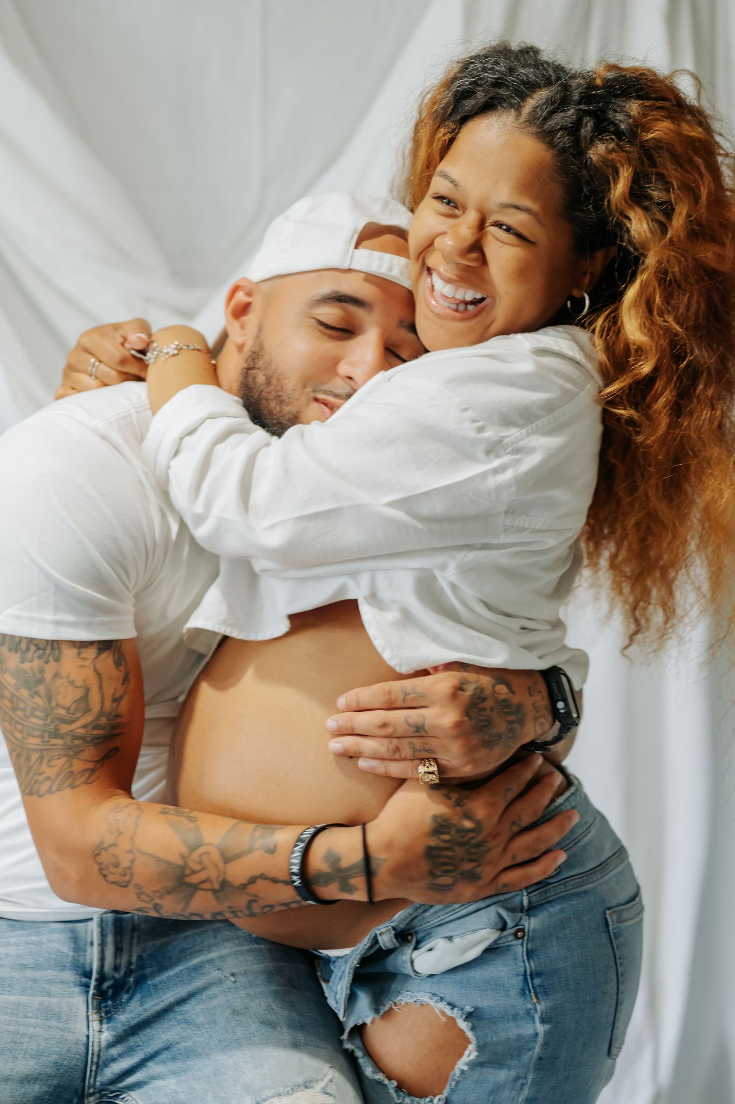 Couple in white shirts and jeans sharing intimate moments in a series of candid poses against white backdrop.