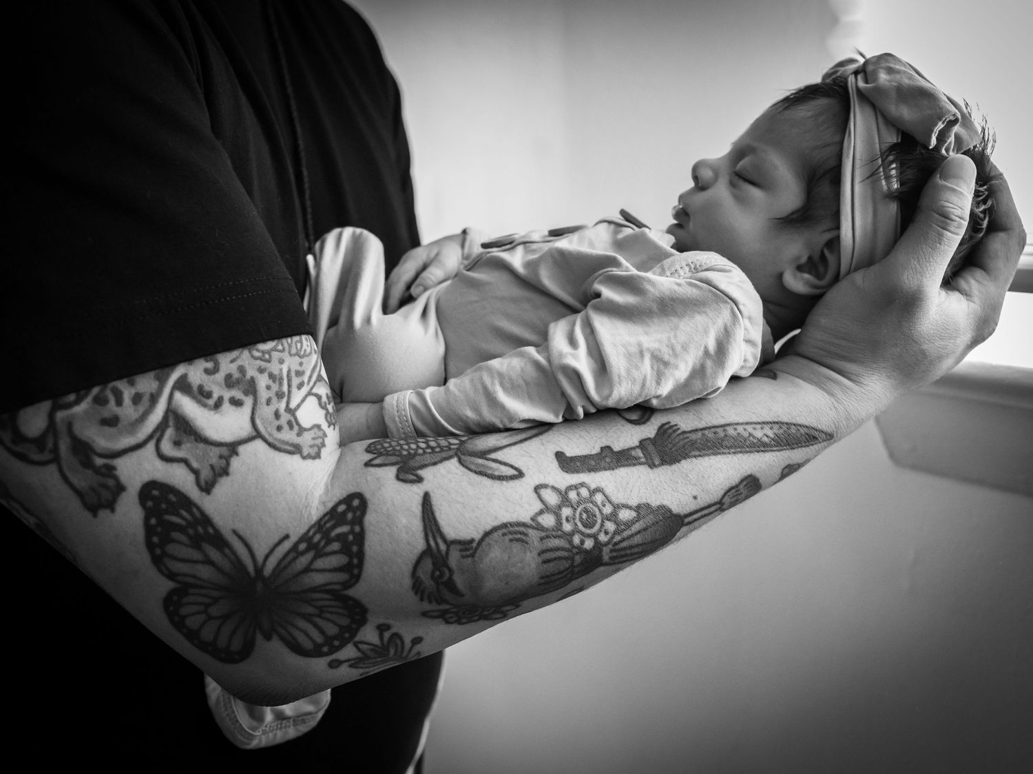 Black and white image of an infant sleeping peacefully on a butterfly-patterned blanket.