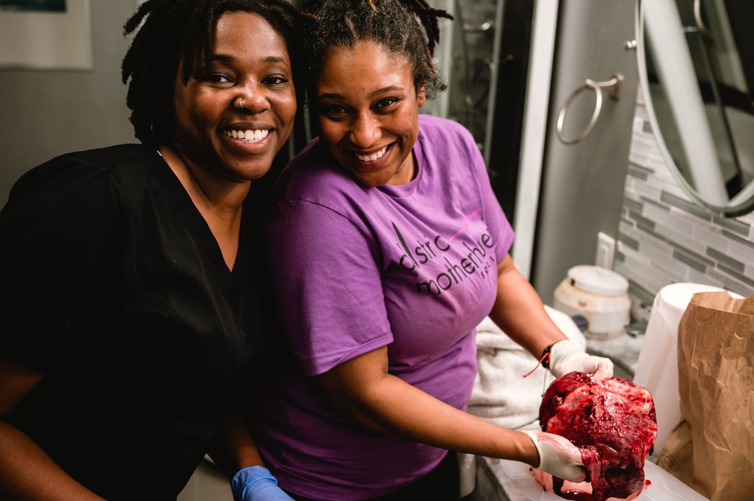 Two people in black and purple shirts sharing a joyful moment in the kitchen.