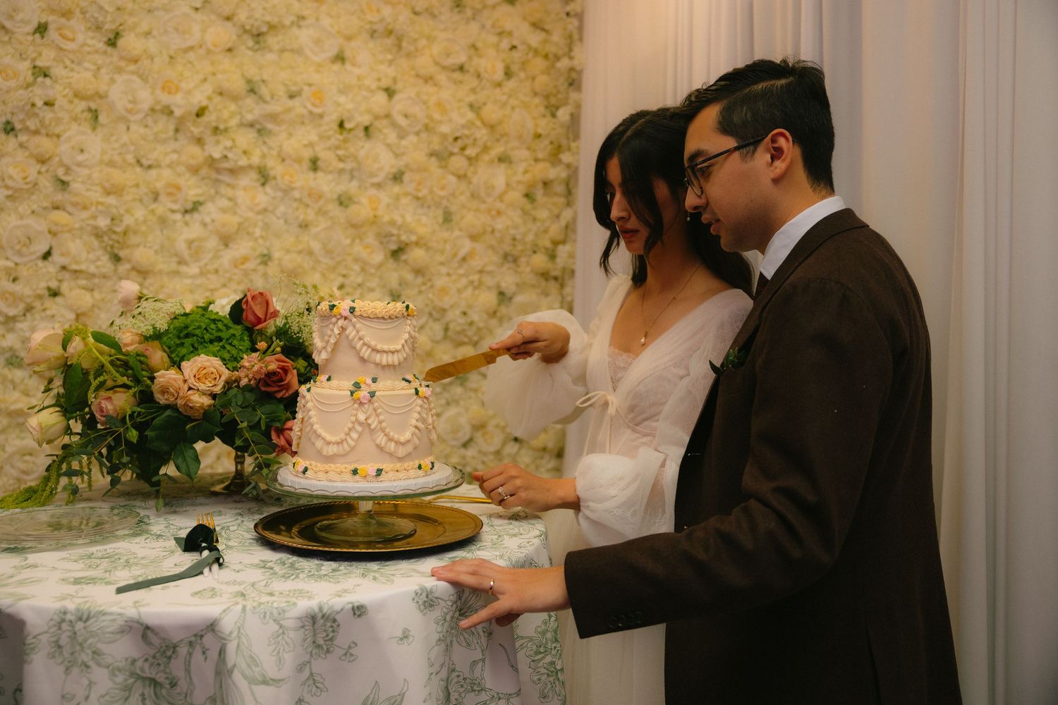 Wedding cake cutting ceremony with elegant white tiered cake on display.