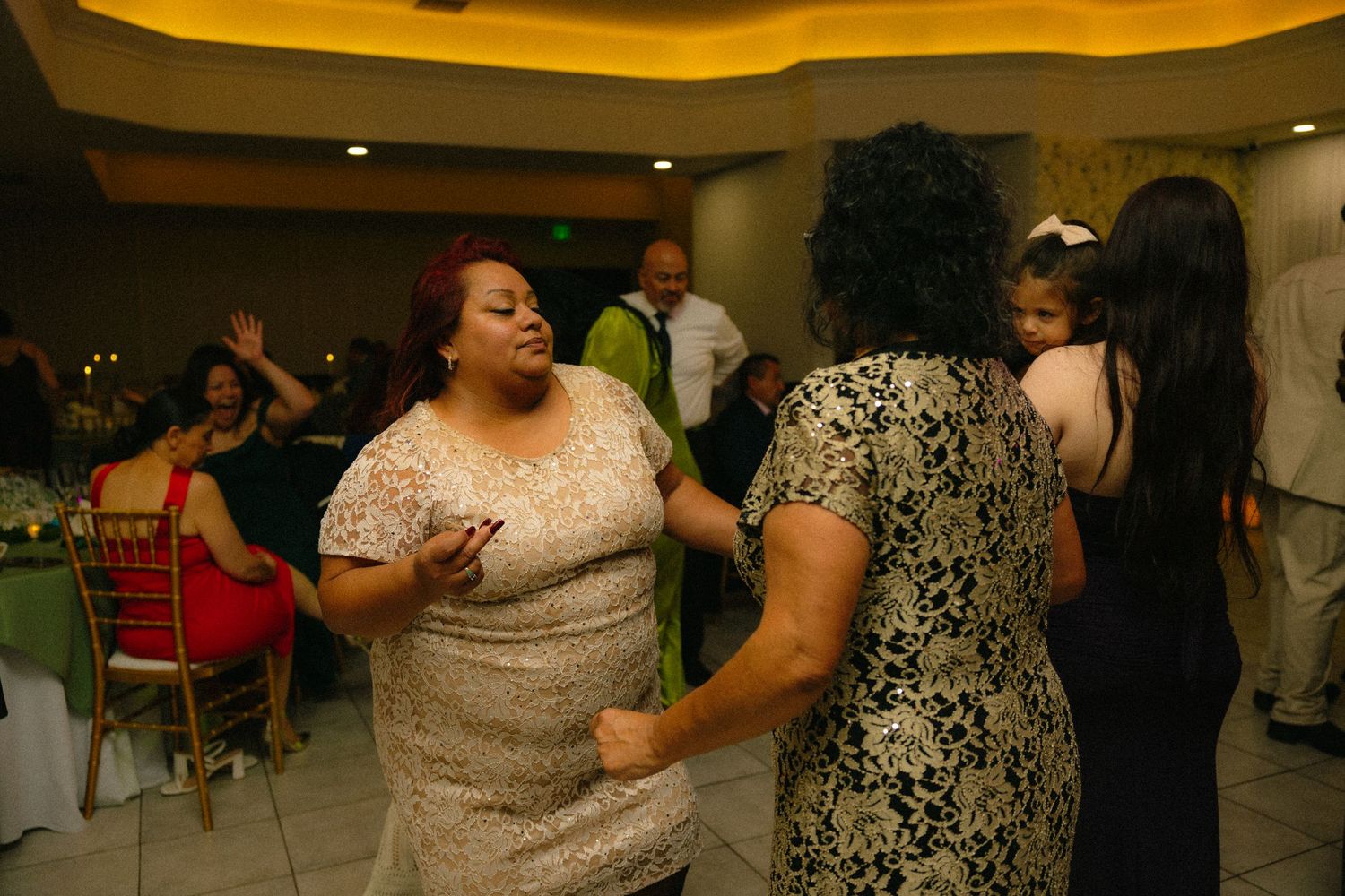 Wedding reception dance floor with guests celebrating in an indoor venue with warm lighting.