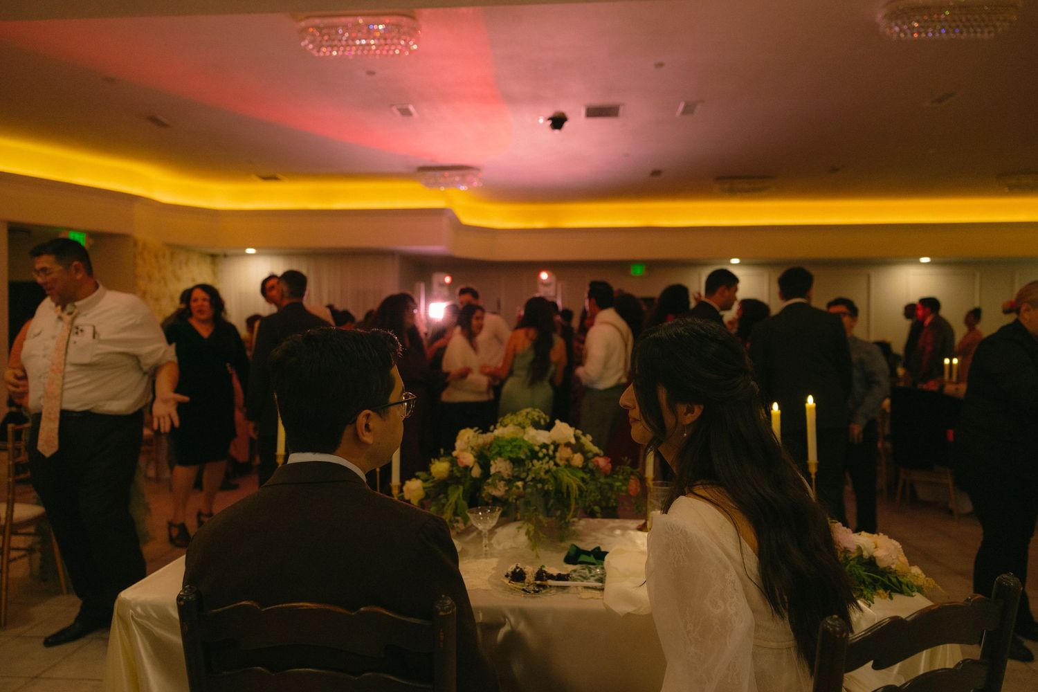 Wedding reception venue with ambient lighting and guests seated at decorated tables.