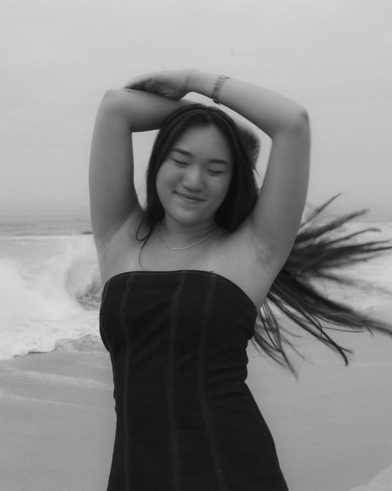 A series of black and white photos showing someone in a black top with flowing hair dancing expressively against a light background.