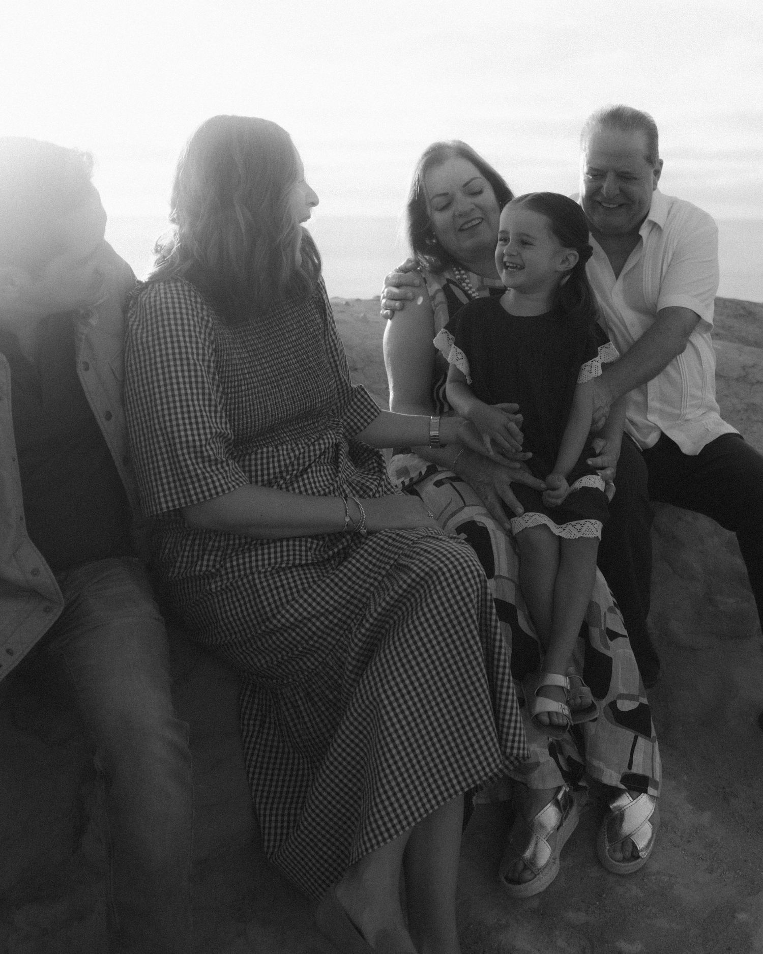 A black and white photo showing people gathered together on an outdoor bench.
