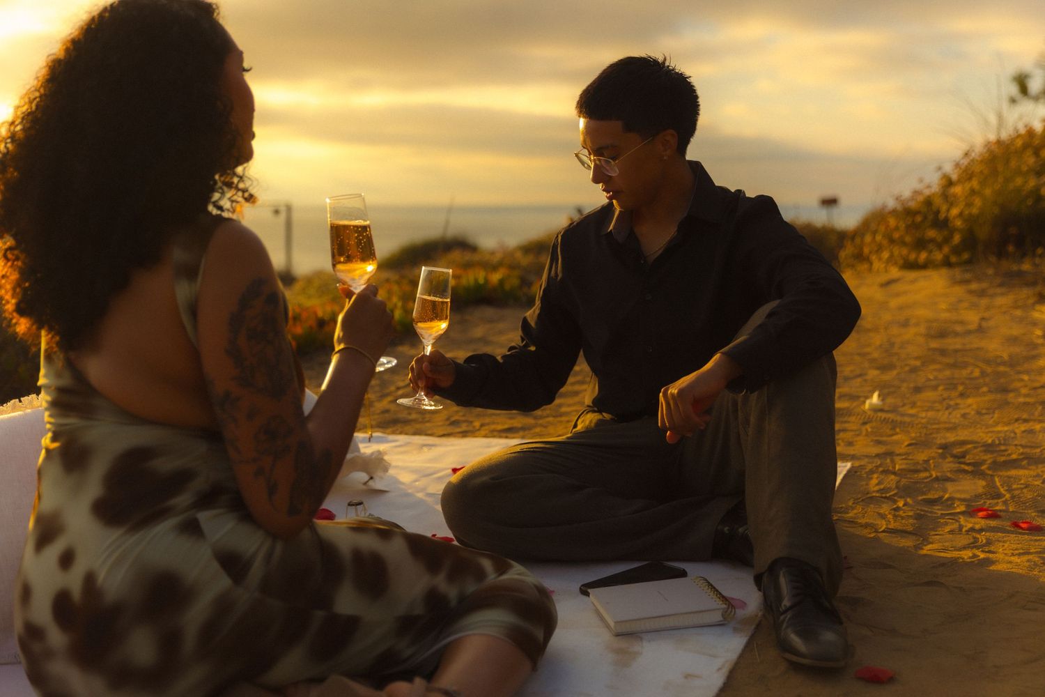 People sharing drinks and enjoying conversation at an outdoor table during golden hour sunset.