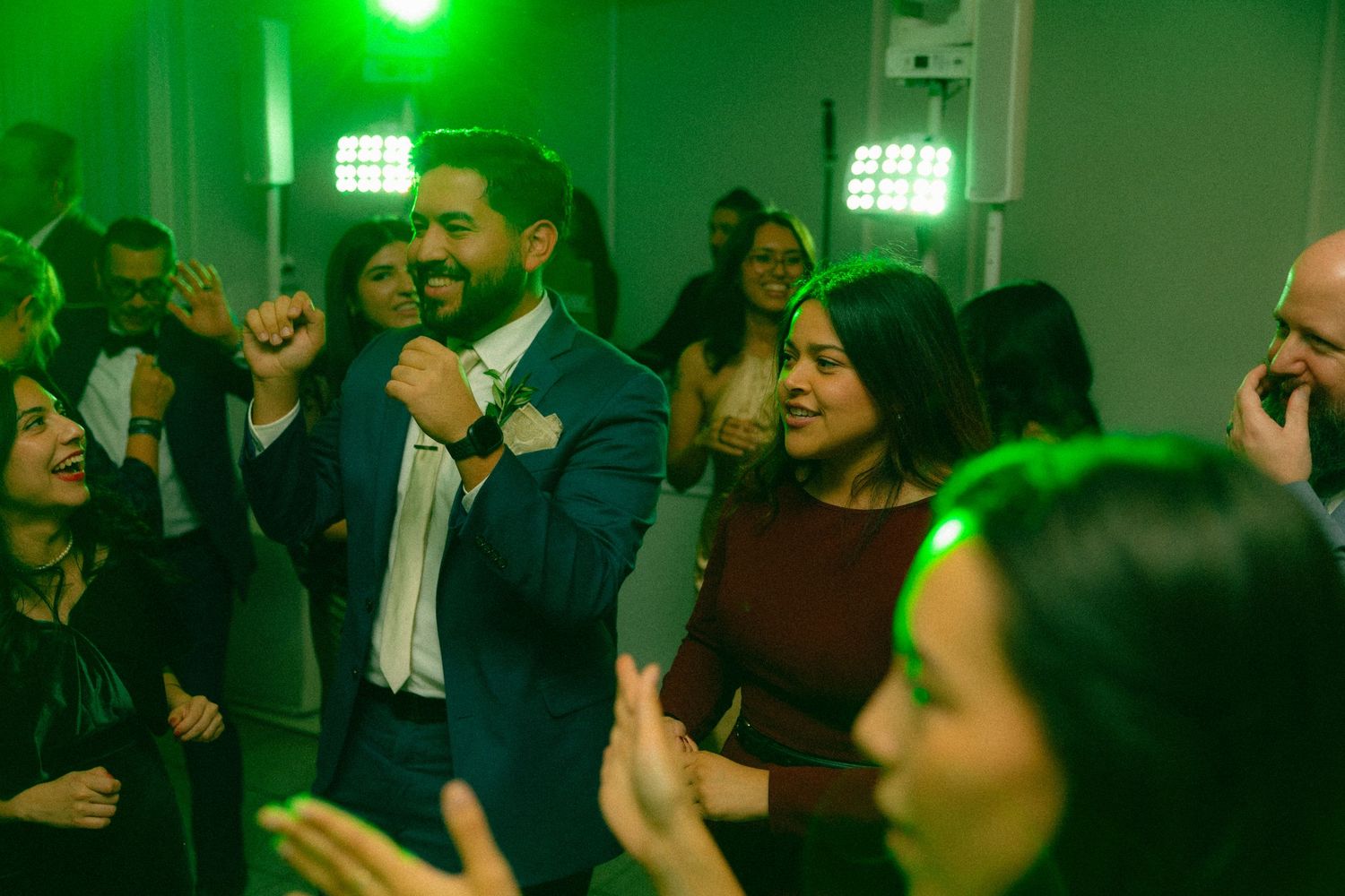Dance party with green lighting and crowd celebrating on dance floor.