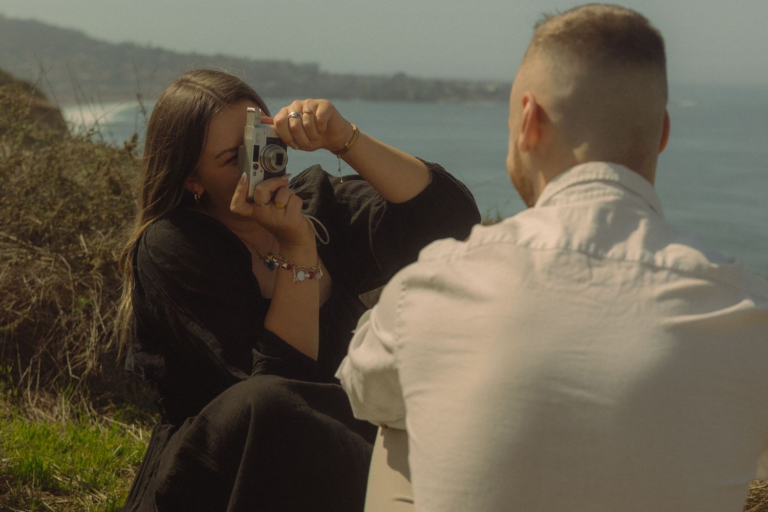 Playful couple sharing romantic moment on coastal clifftop overlook.