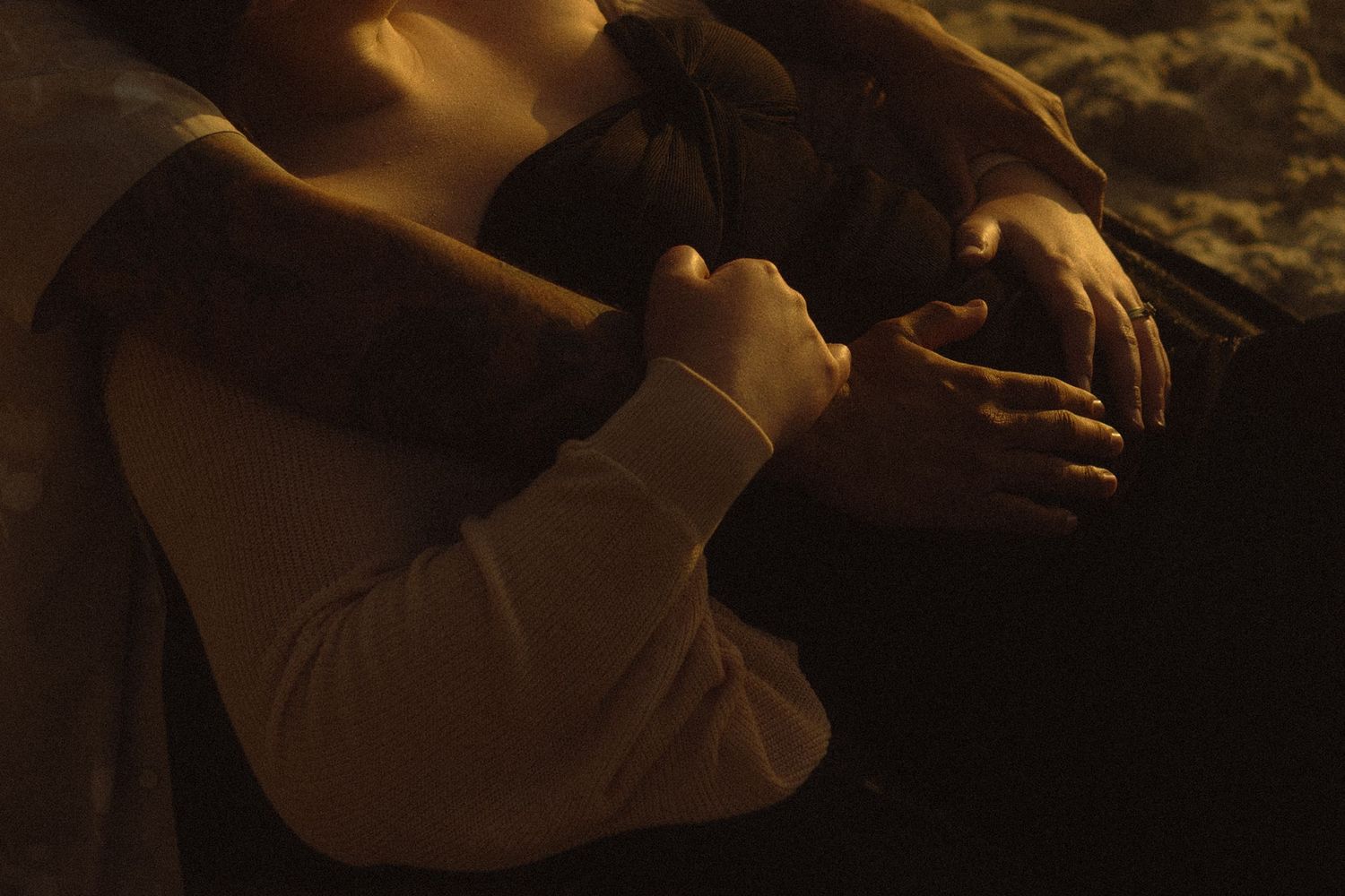 A cinematic close-up of hands holding a warm drink in dim, atmospheric lighting.