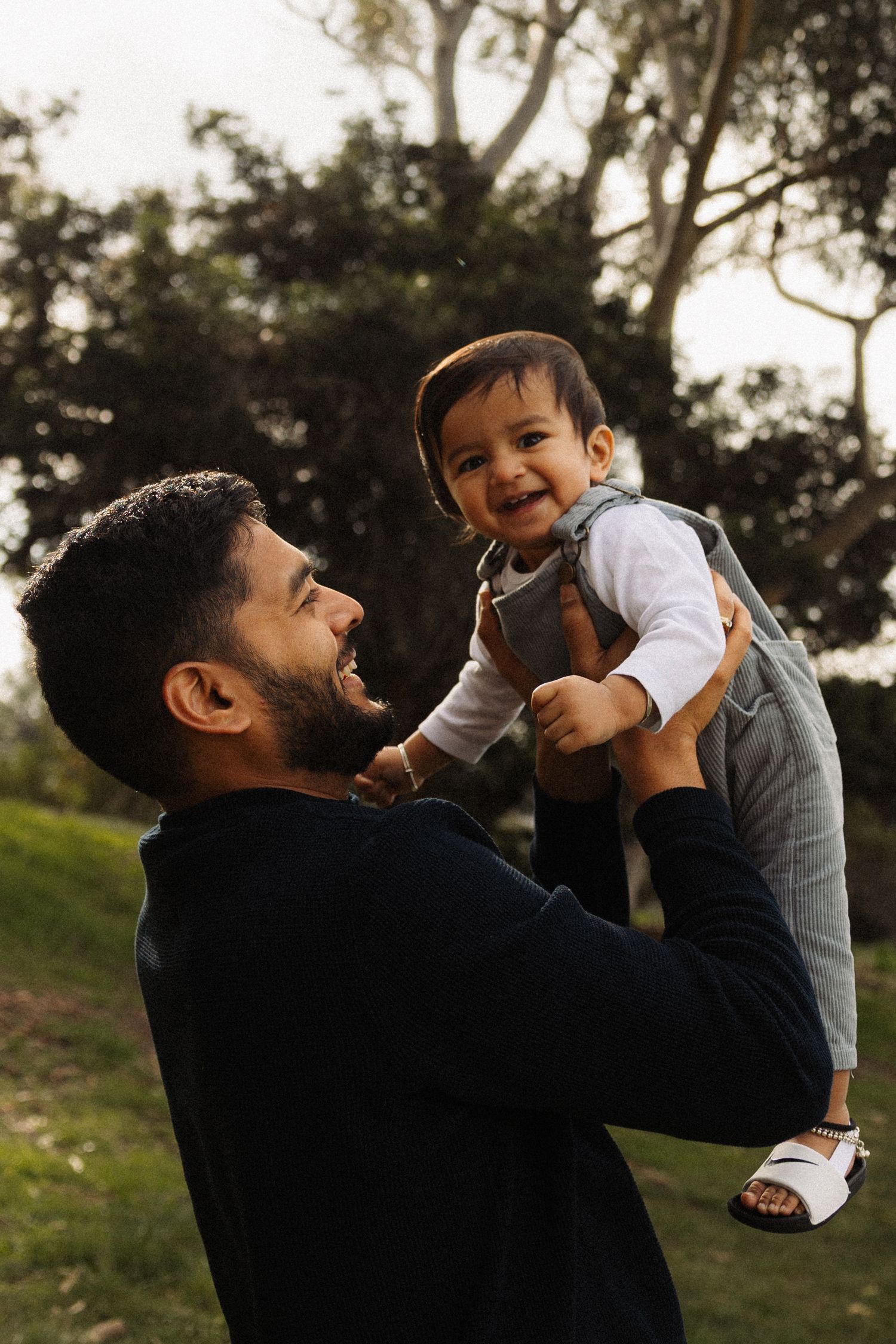 A series of candid moments showing a father lifting and playing with his small child outdoors during sunset.