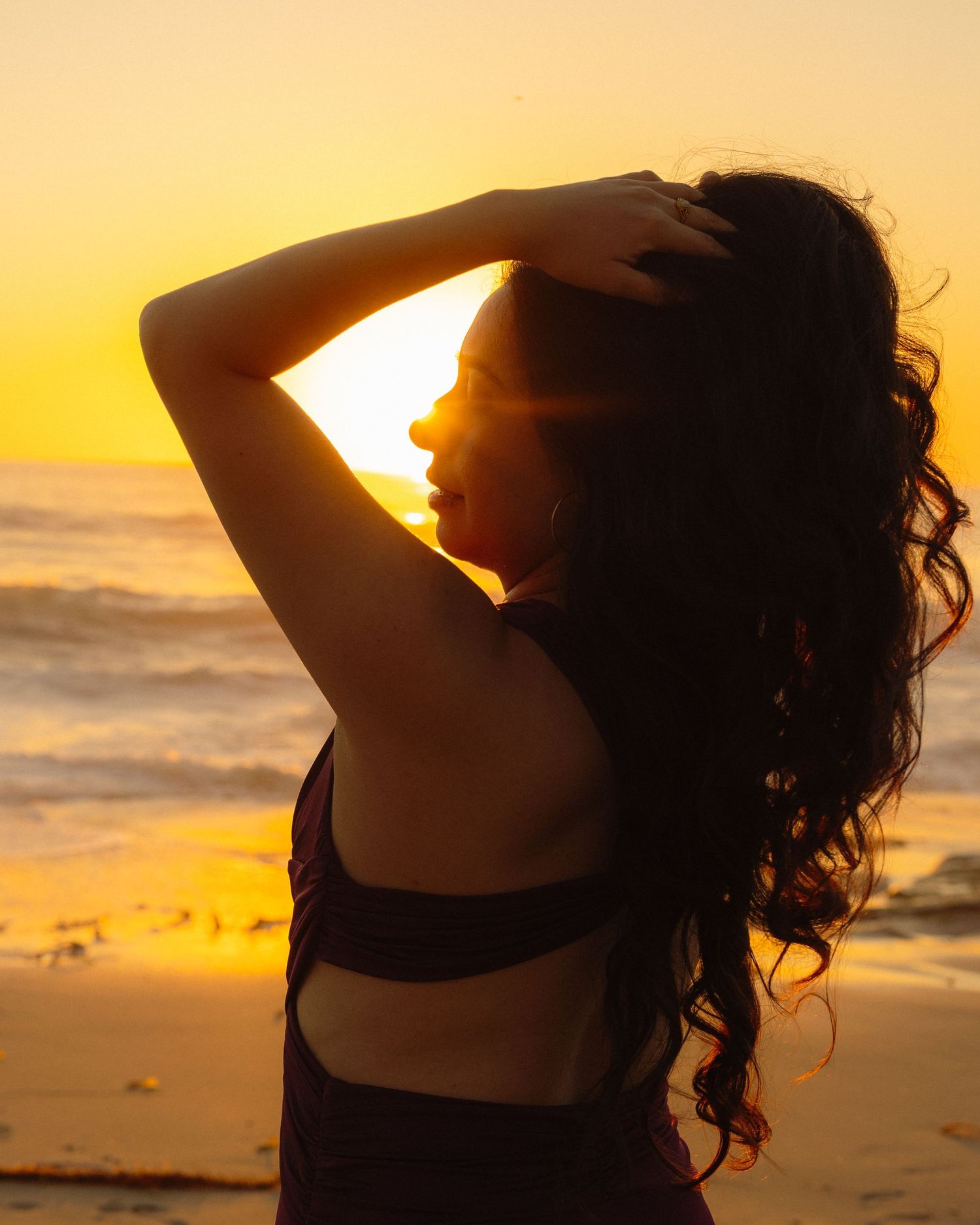 A silhouetted figure stands on a beach at sunset with golden light reflecting off the ocean waves.