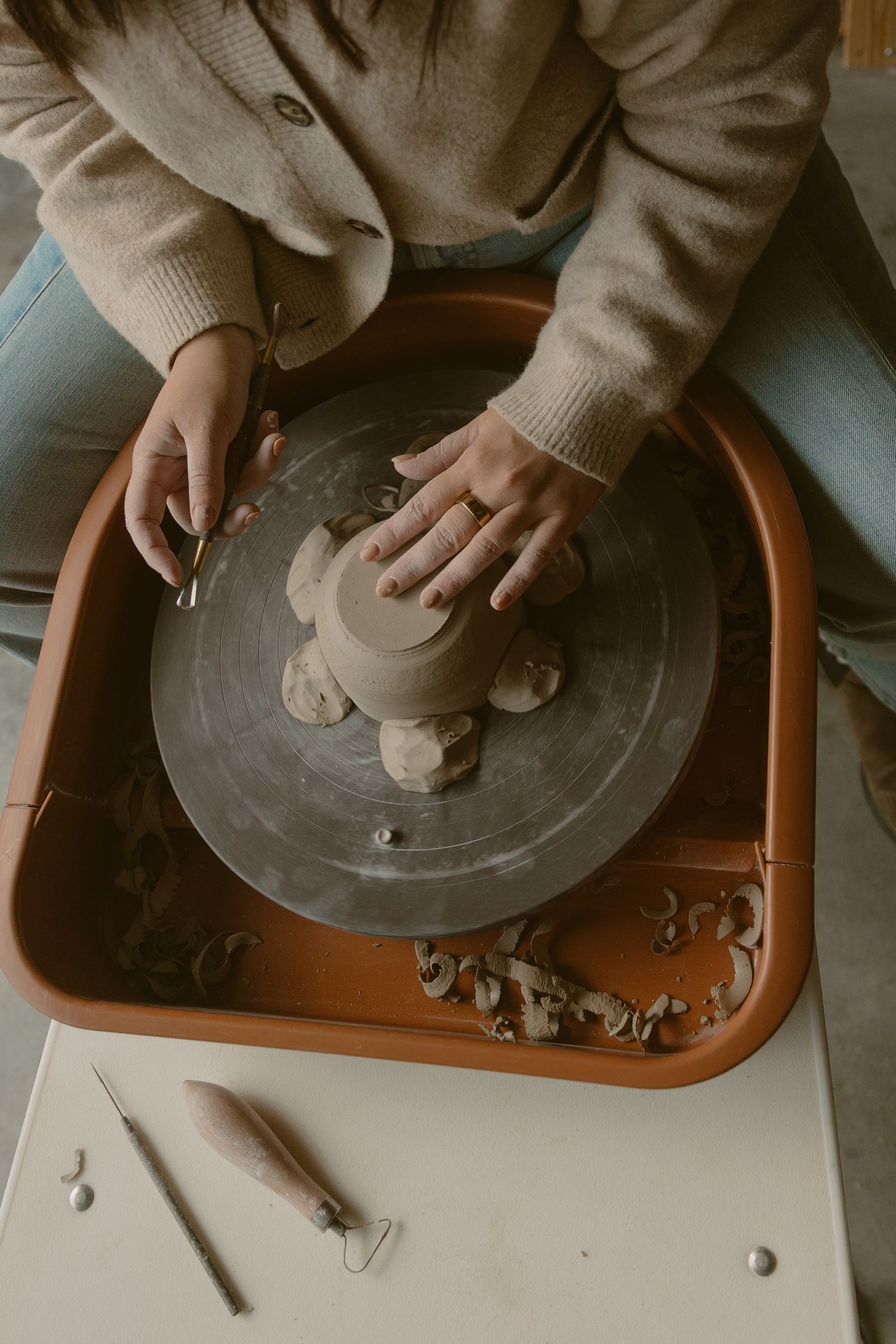Overhead view of hands sculpting clay on a pottery wheel.