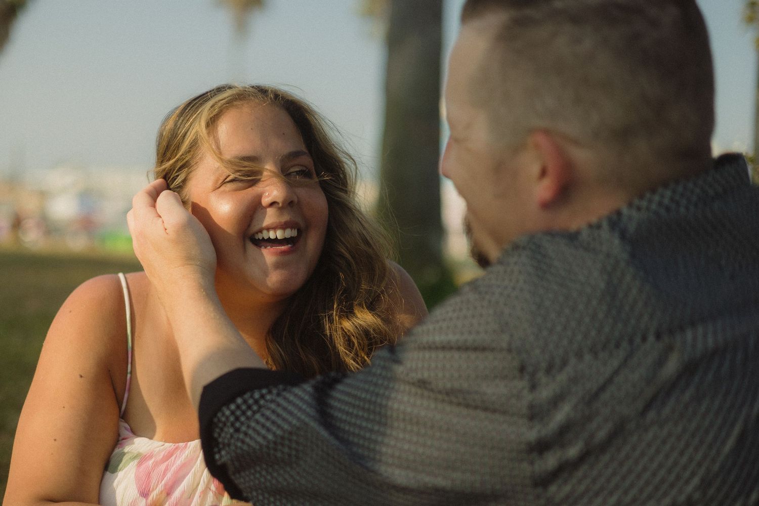 A joyful couple shares a tender moment together while sitting outdoors during golden hour.