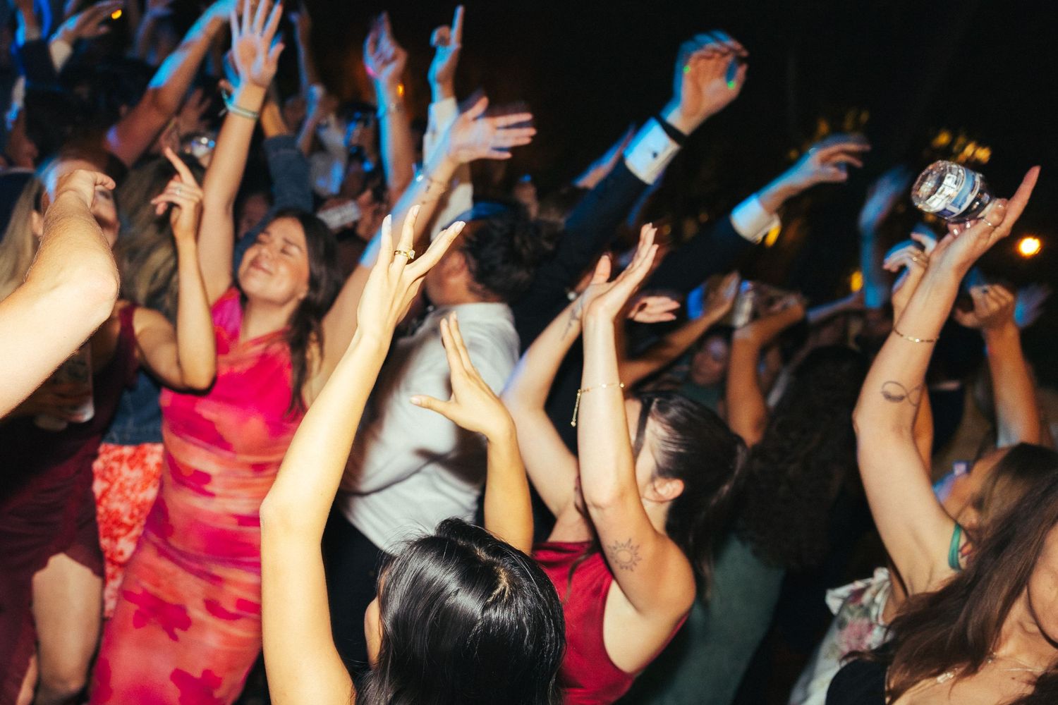 Crowd of guests dancing with hands raised at a lively party celebration event.