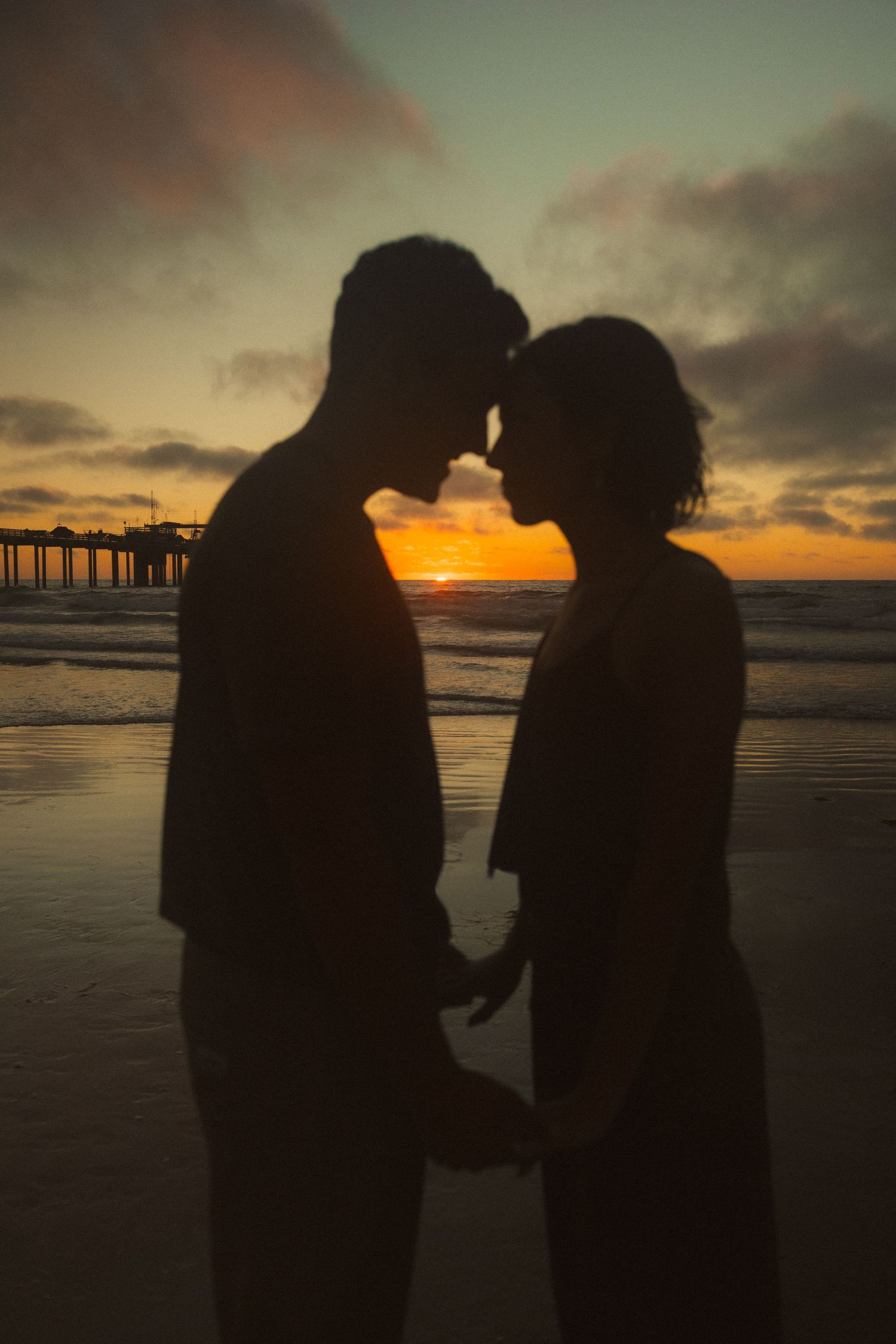 Silhouetted couple on beach at sunset creating romantic atmosphere.