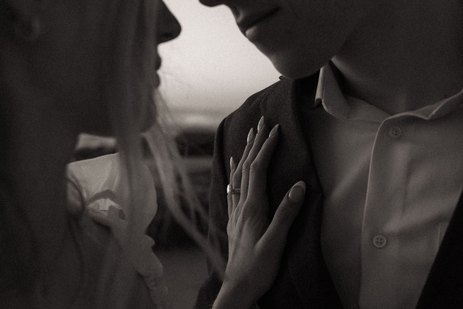 Black and white photo of a couple in an intimate moment, with a woman's hand gently resting on a man's chest.