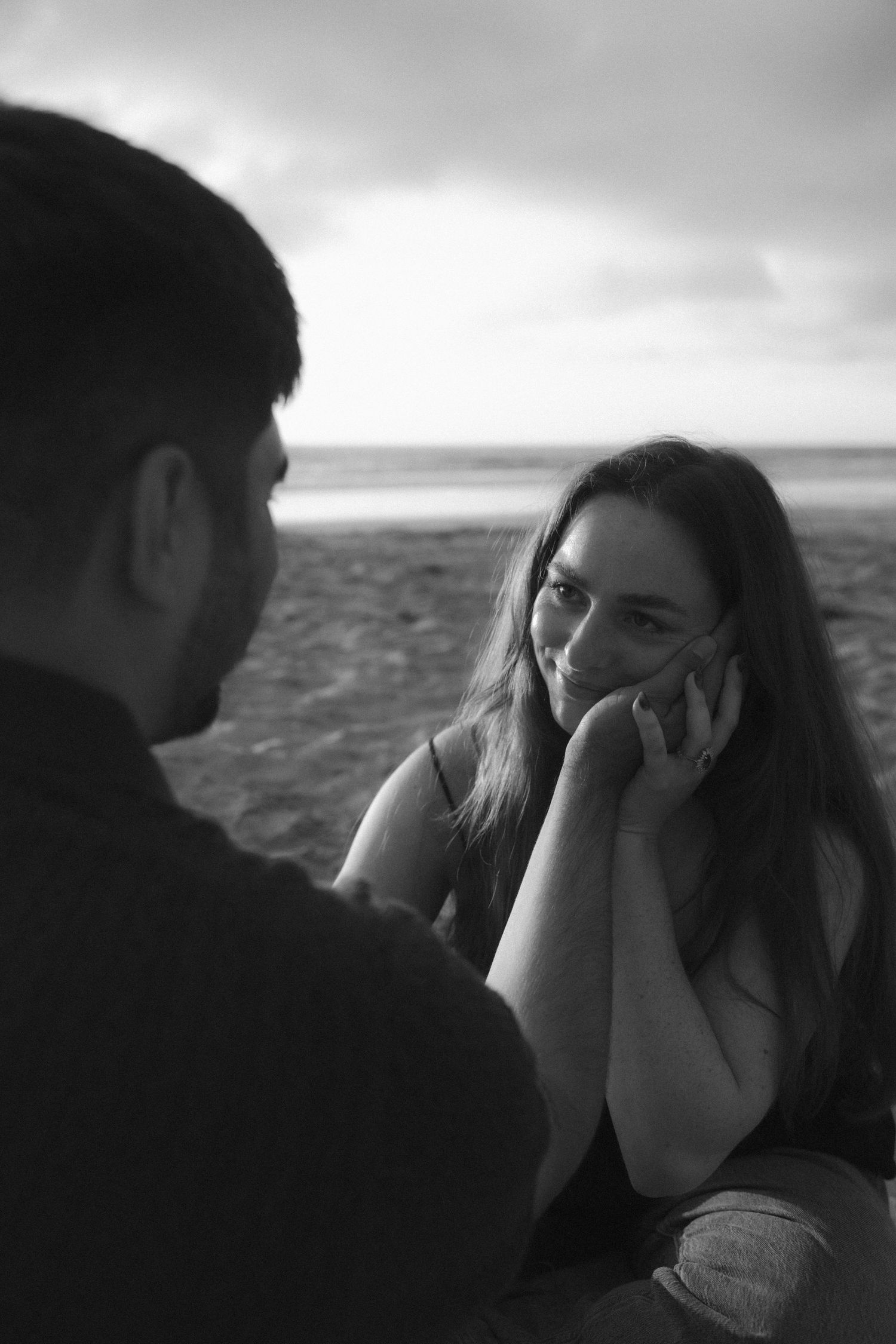 A series of black and white photos showing a couple sharing an intimate moment by the ocean.