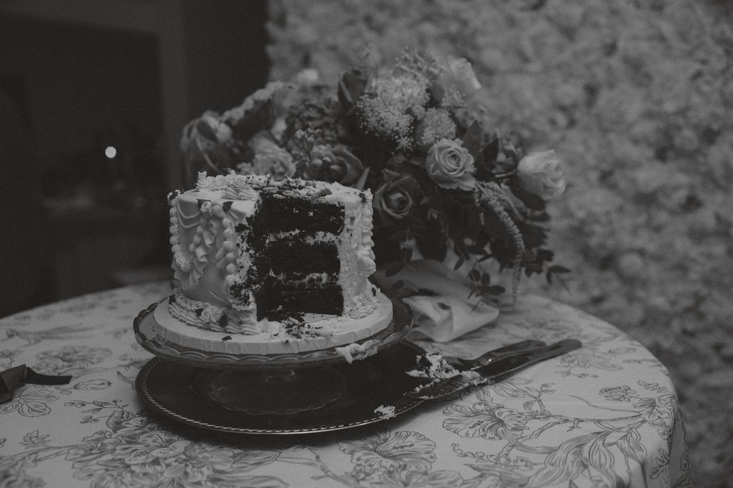 Close-up of elegant wedding cake details on textured tablecloth.