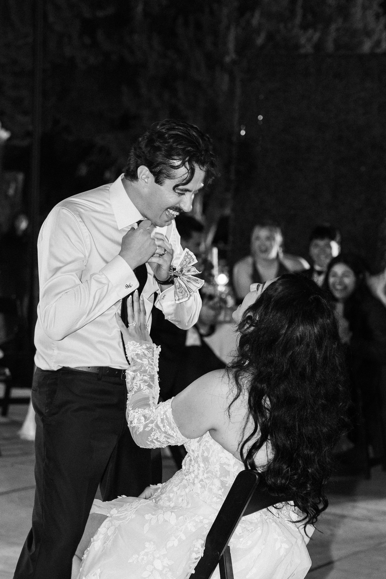 Black and white photo of bride and groom sharing a joyful first dance moment at their wedding reception.