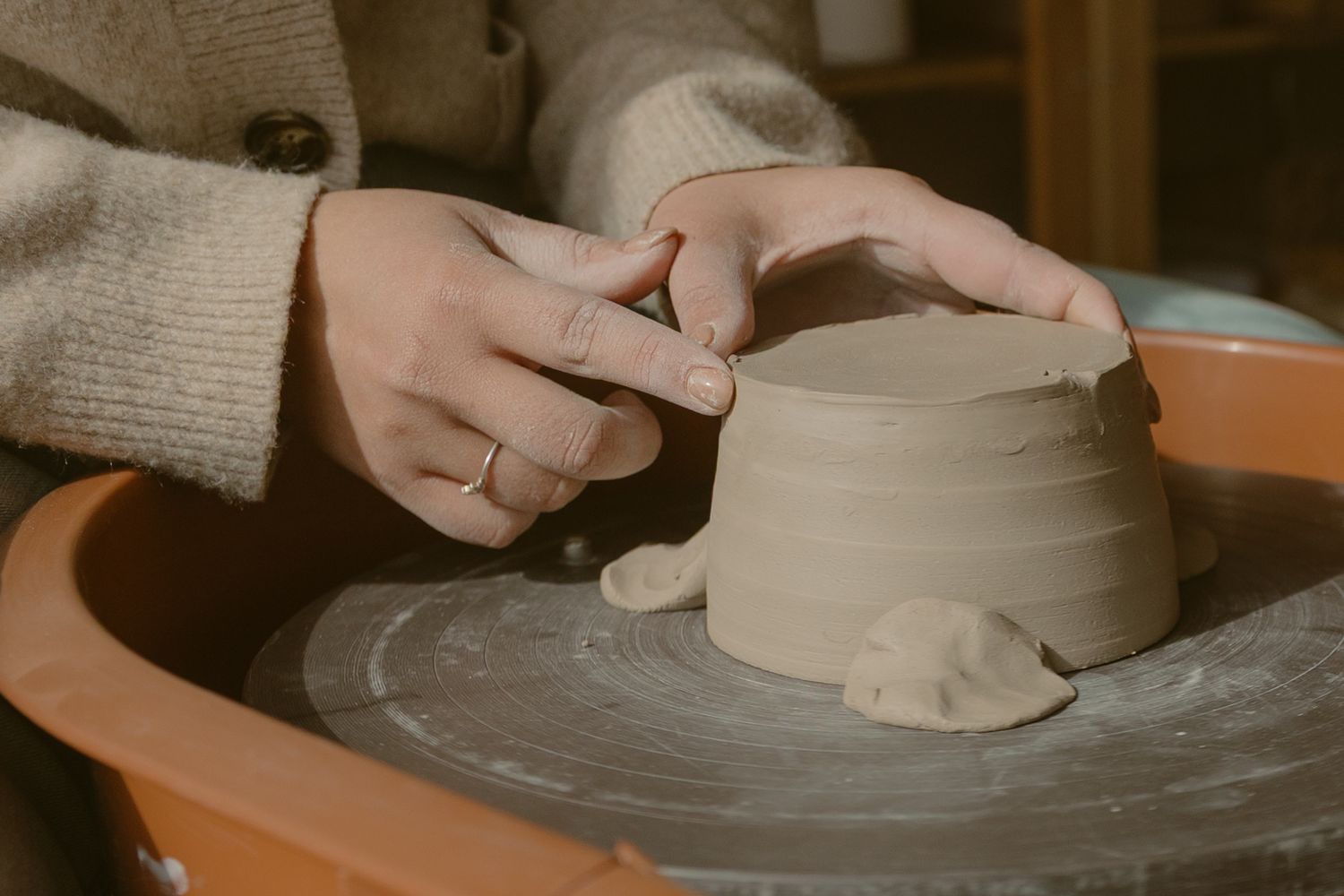 Hands sculpting clay vessel on pottery wheel with focused detail for a branding session