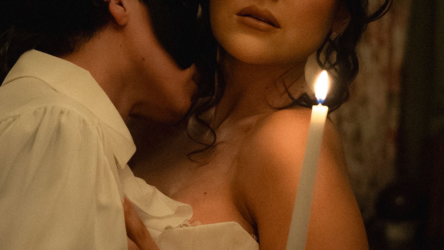 A soft candlelit ambiance illuminates figures in an intimate indoor setting.