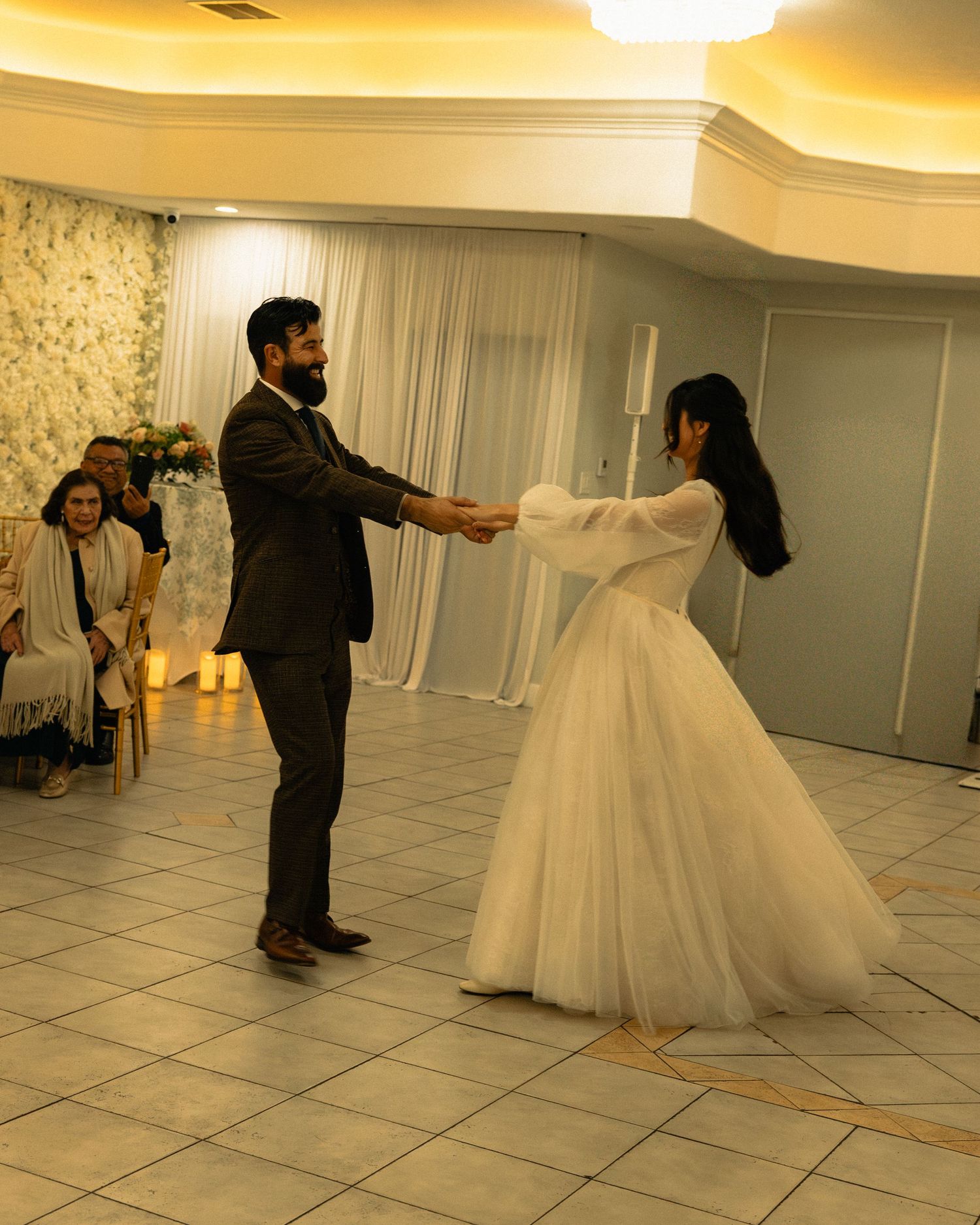 Wedding couple dancing together on a tiled ballroom floor during their first dance.