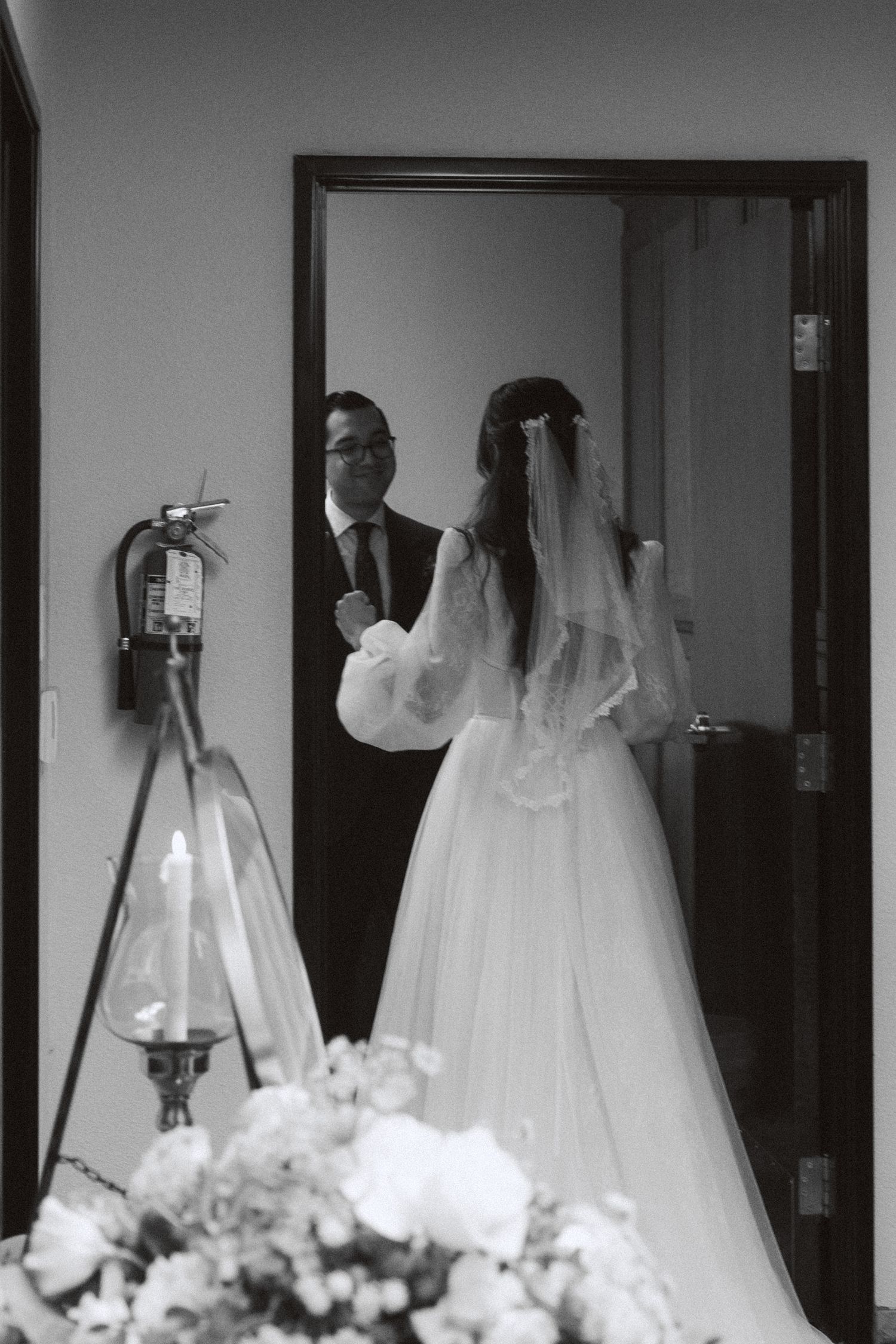Wedding dresses on hangers displayed in a row with floral arrangements beneath them.