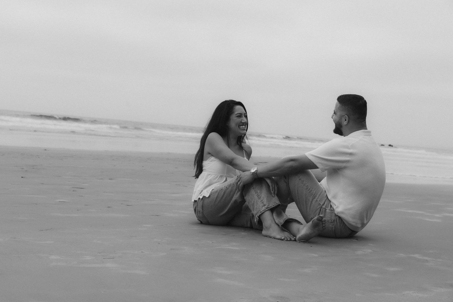 A couple relaxes together on a sandy beach while enjoying a romantic moment at sunset.