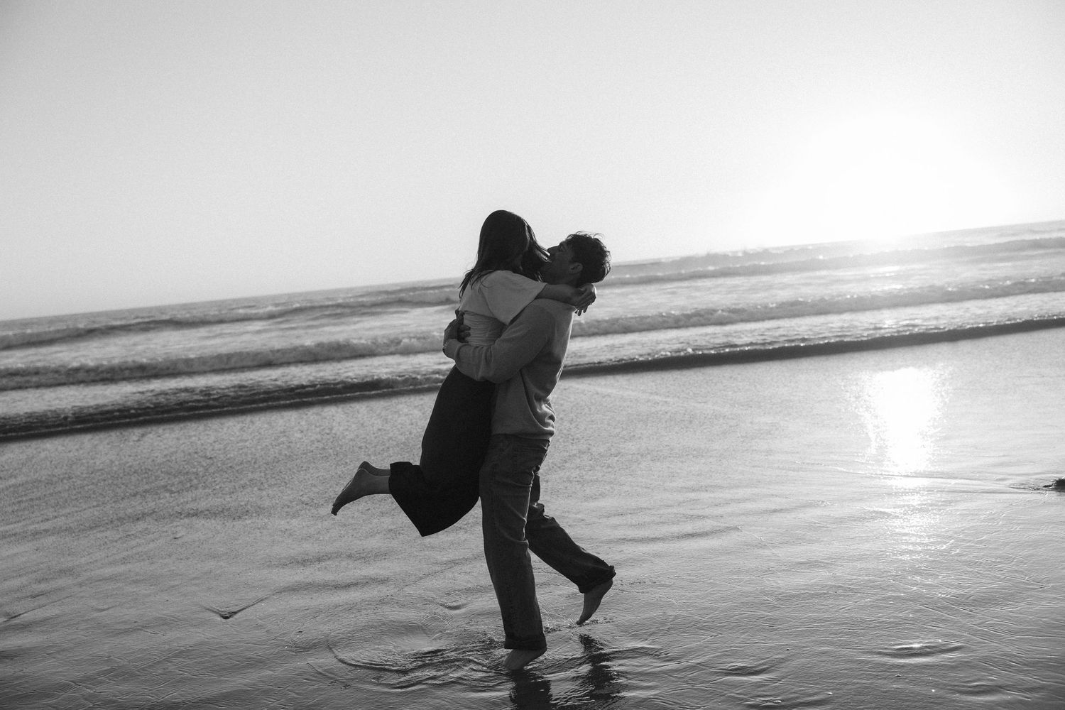 Silhouettes of a couple embrace on a beach at sunset creating romantic seaside moments.
