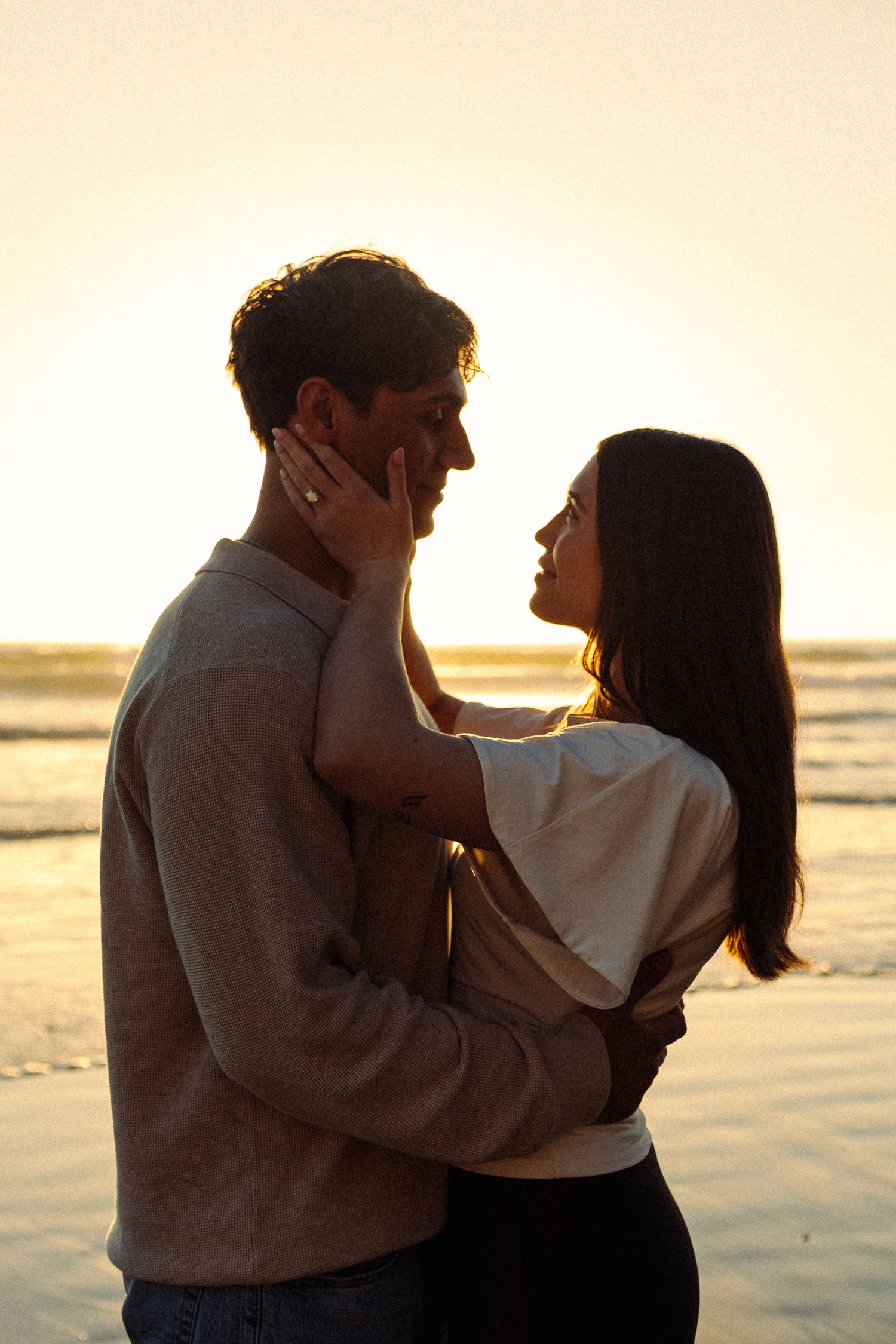 A romantic couple embraces on a beach at sunset in a series of silhouetted poses.