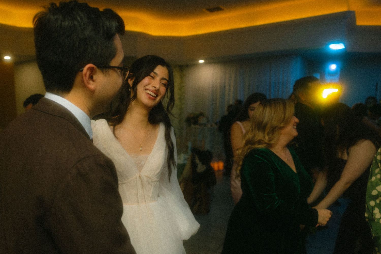 Wedding reception venue with warm amber lighting and guests dancing.