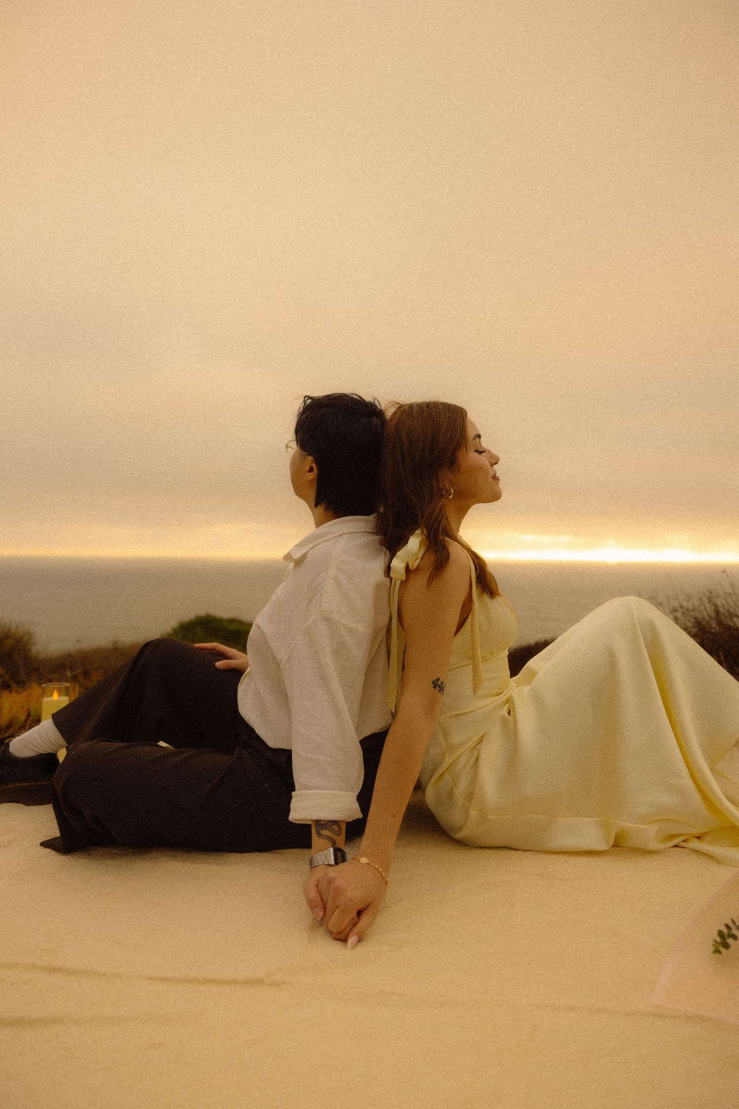 Four artistic photos show figures in white and yellow clothing lying down against a warm beige background at sunset.