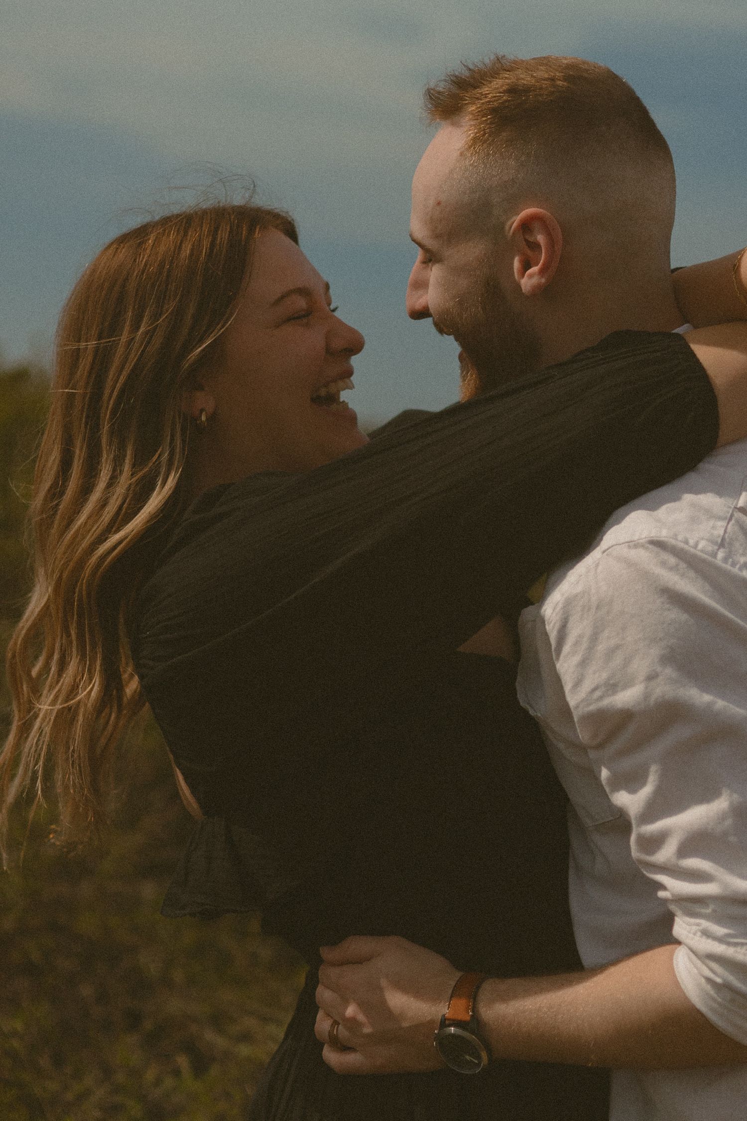 Romantic couple embracing and laughing together in warm sunset light.