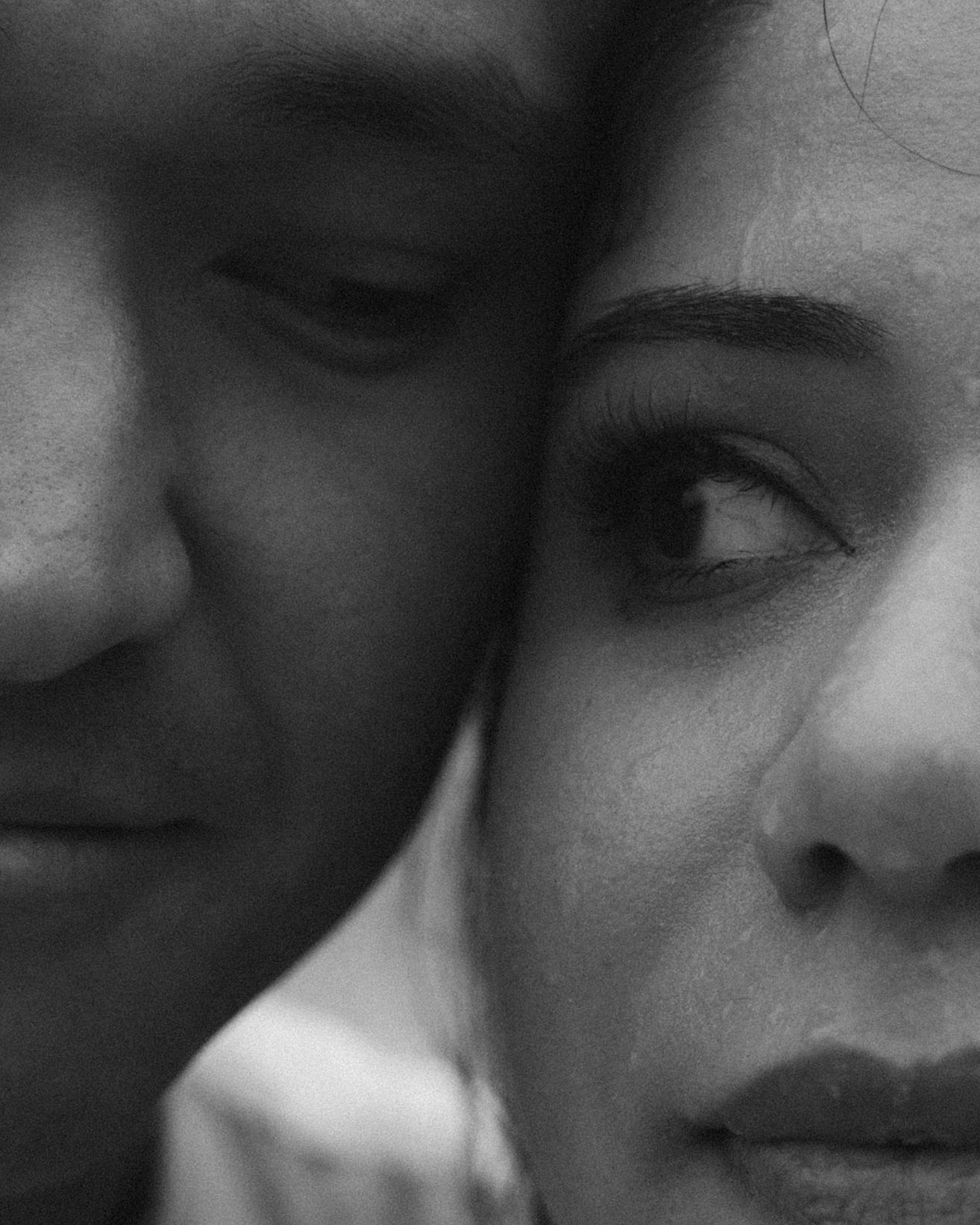 Black and white close-up portrait showing half of a person's face with soft lighting and shadows.